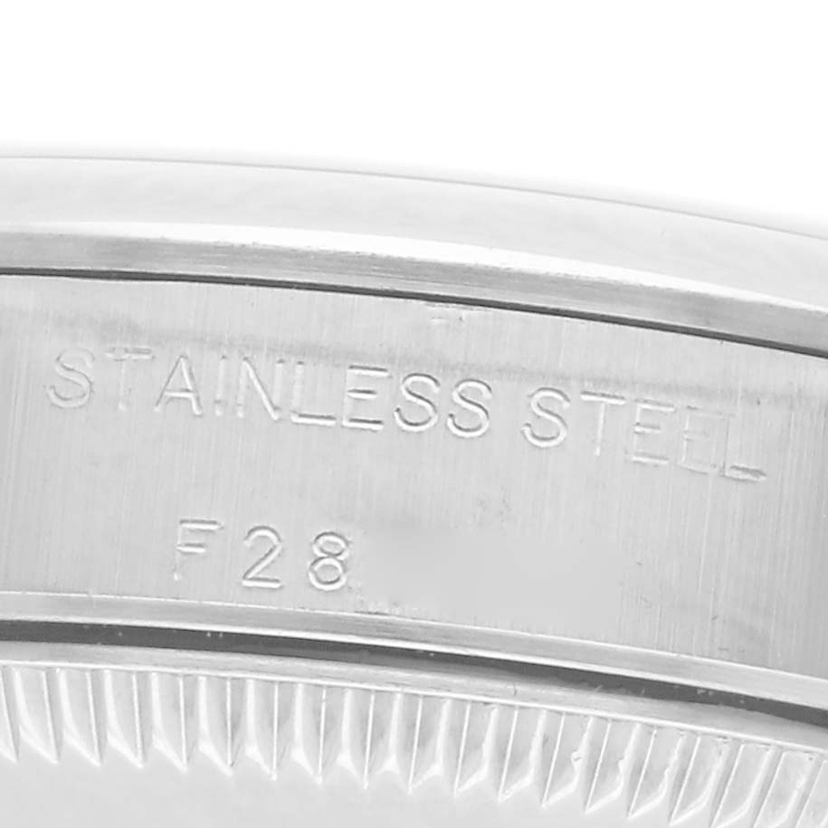 The image shows a close-up of the case back edge of the Rolex Oyster Perpetual 76080 Women
s Stainless Steel Blue Dial 76080 Women
s Stainless Steel Blue Dial, displaying "Stainless Steel" and "F28".