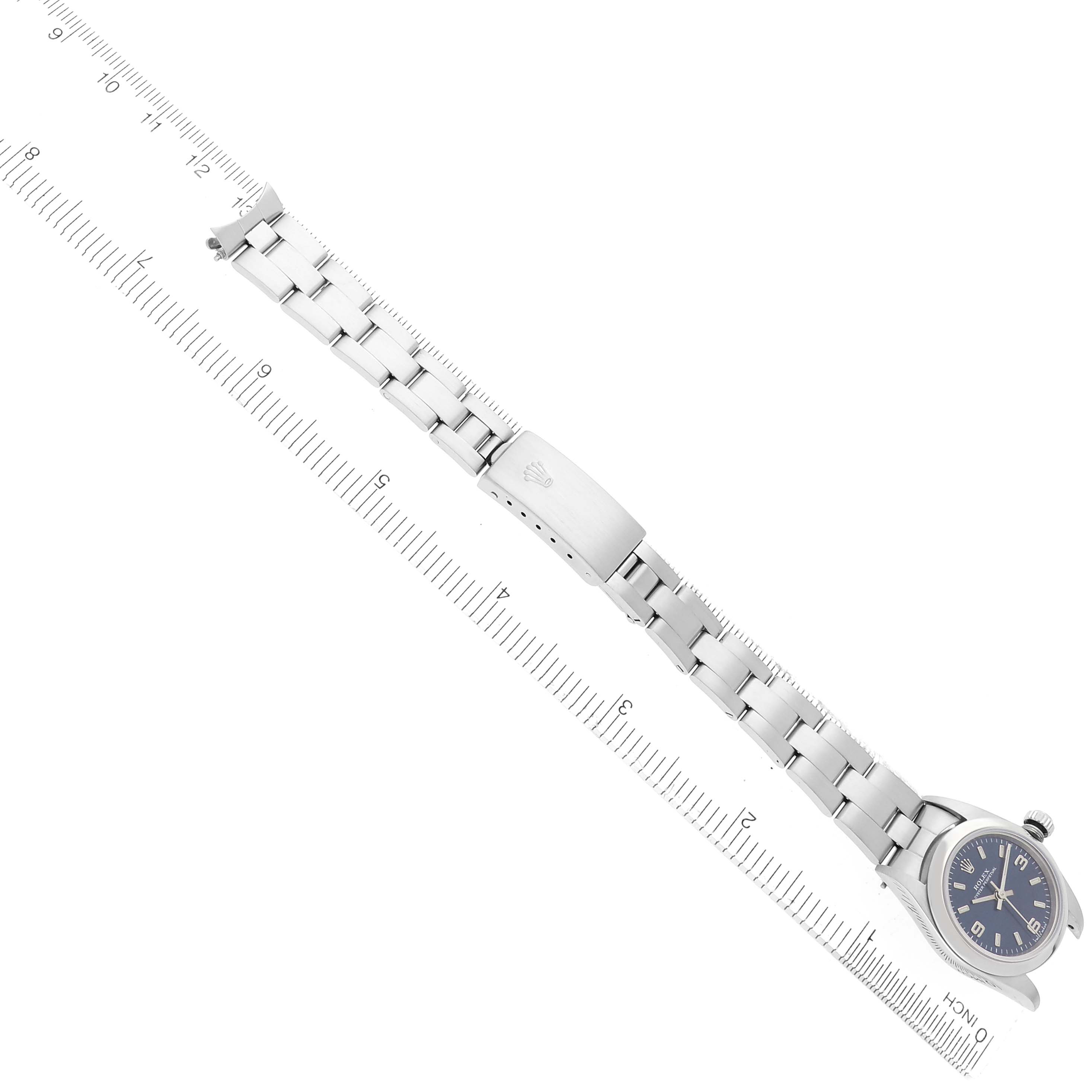 The image shows the Rolex Oyster Perpetual 76080 Women
s Stainless Steel Blue Dial 76080 Women
s Stainless Steel Blue Dial watch laid flat with its bracelet and clasp alongside a ruler for scale.