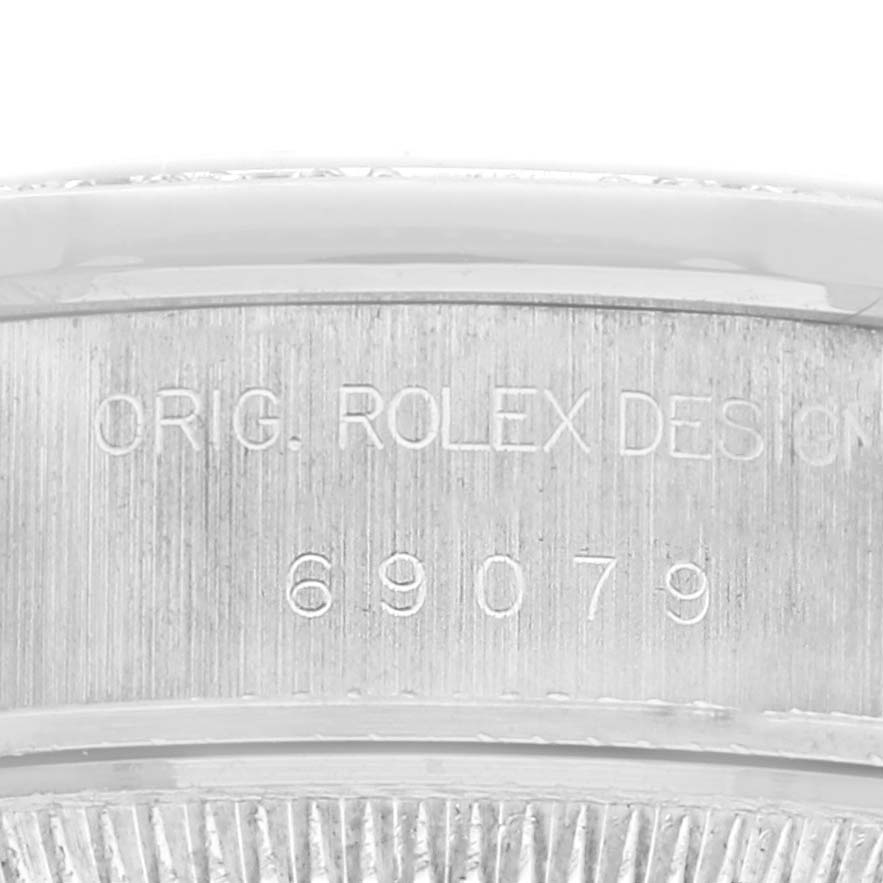 The image shows a close-up of the engraved edge on a Rolex President 69079 Women
s White Gold Silver Dial 69079 Women
s White Gold Silver Dial watch, highlighting "ORIG. ROLEX DESIGN 69079".
