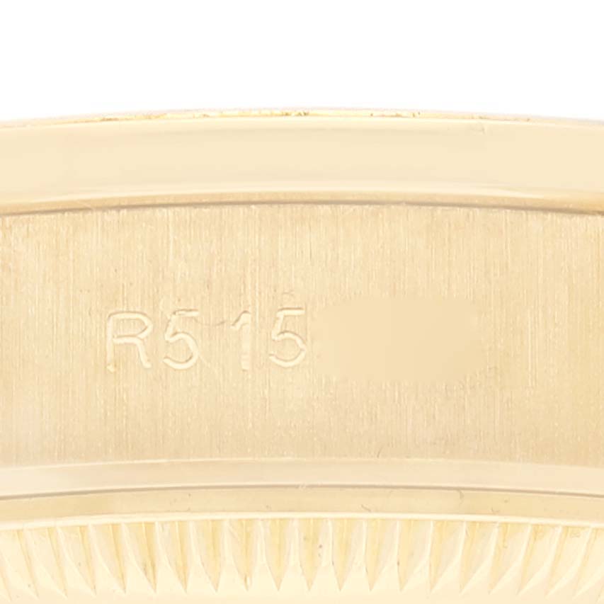The image shows a close-up of the side of the Rolex President 69138 Women's Yellow Gold Blue Dial 69138 Women's Yellow Gold Blue Dial watch, including engraving and part of the bezel.