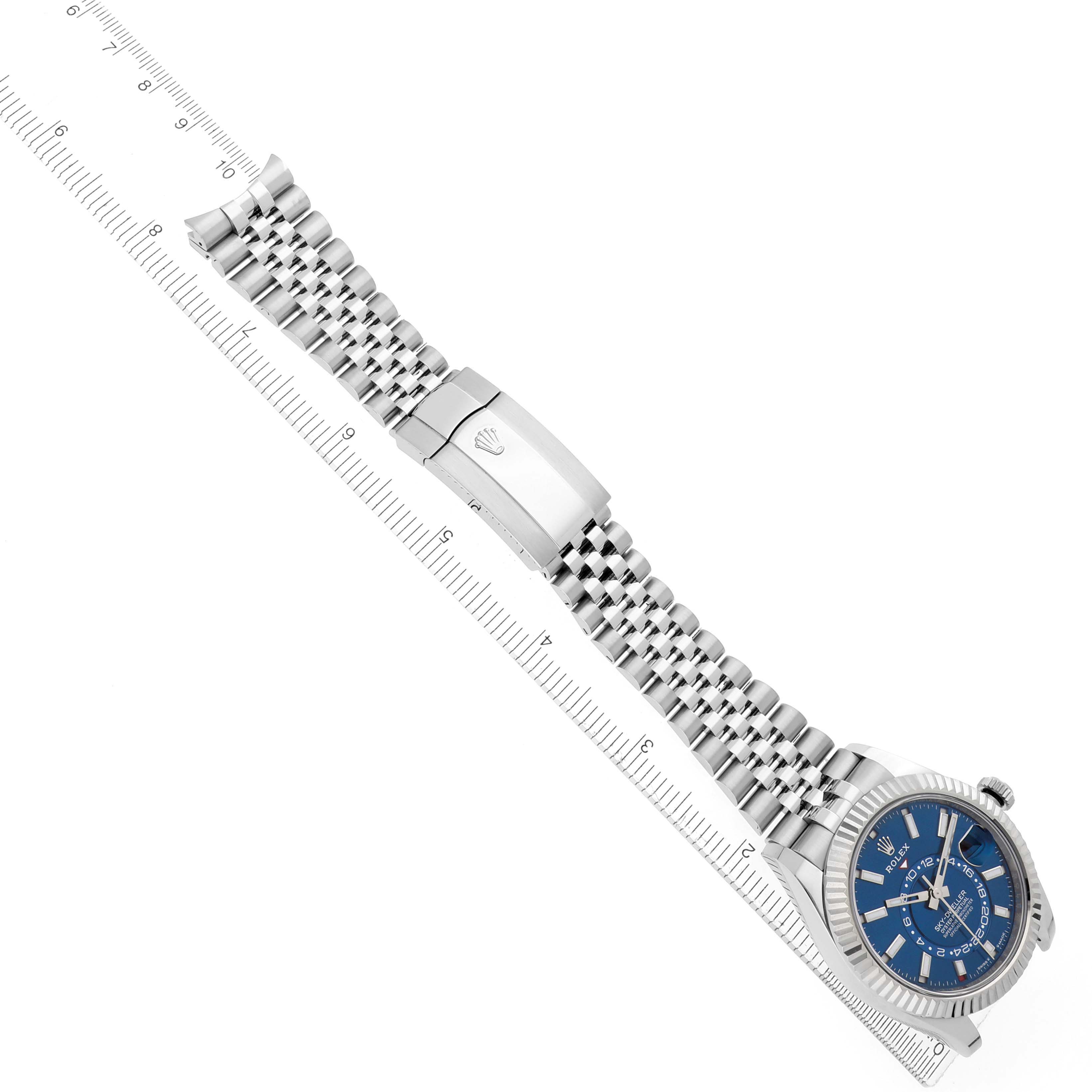 The image shows the Rolex Sky-Dweller 336934 Men
s Stainless Steel Blue Dial 336934 Men
s Stainless Steel Blue Dial watch at a diagonal angle, displaying the dial, bracelet, and clasp beside a ruler.