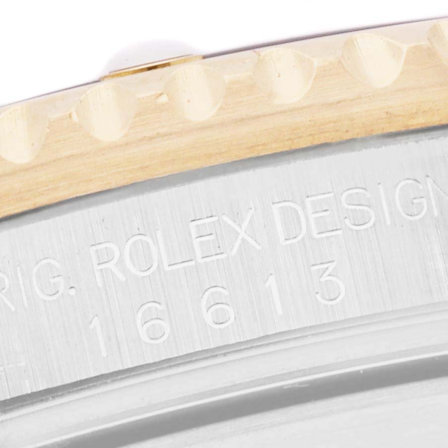The image shows a close-up of the side engraving and bezel of a Rolex Submariner 16613 Men
s Steel and Gold (two tone) Champagne Dial 16613 Men
s Steel and Gold (two tone) Champagne Dial watch.