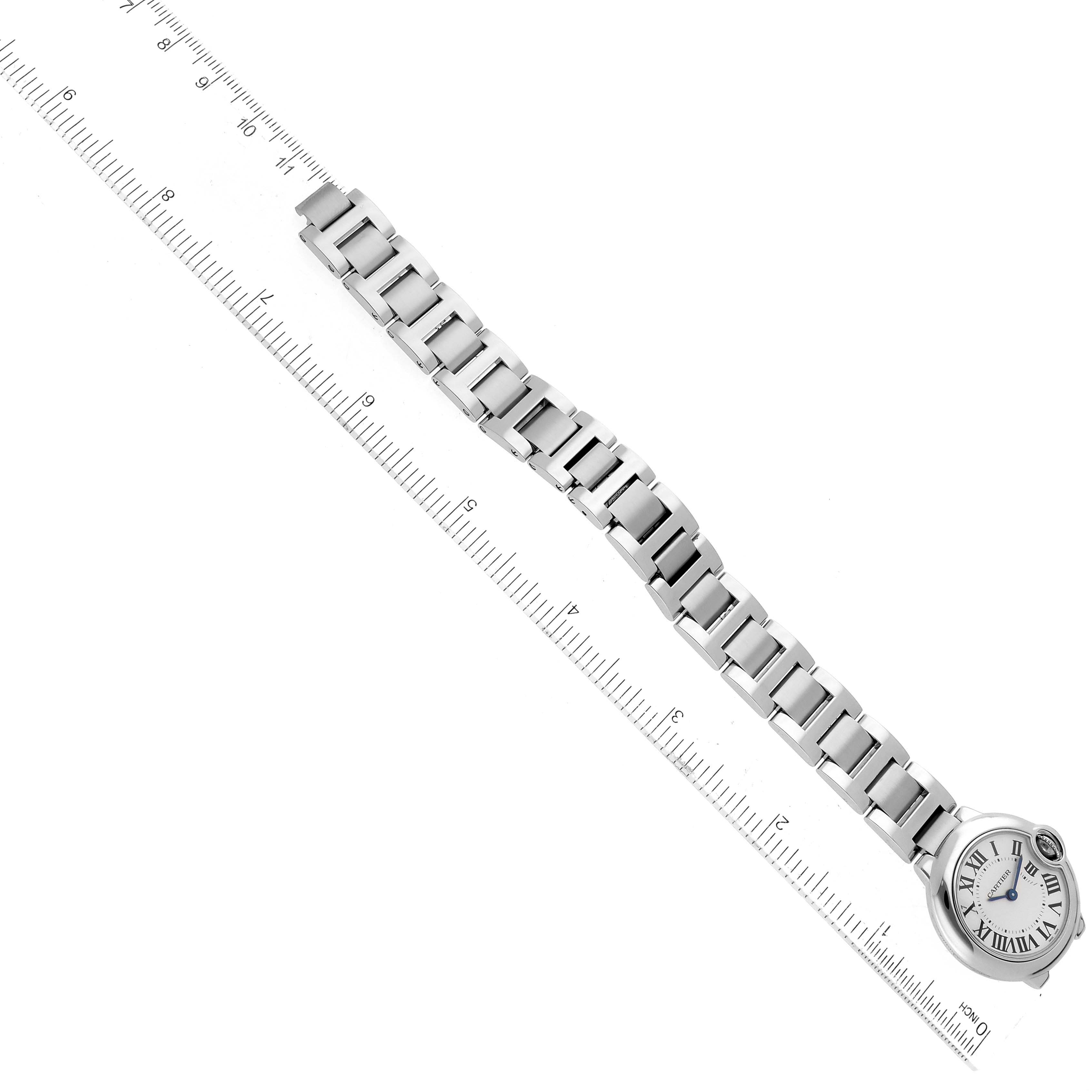 This image shows the Ballon Bleu watch by Cartier laid flat with a ruler for measurement, displaying its face and metal bracelet.