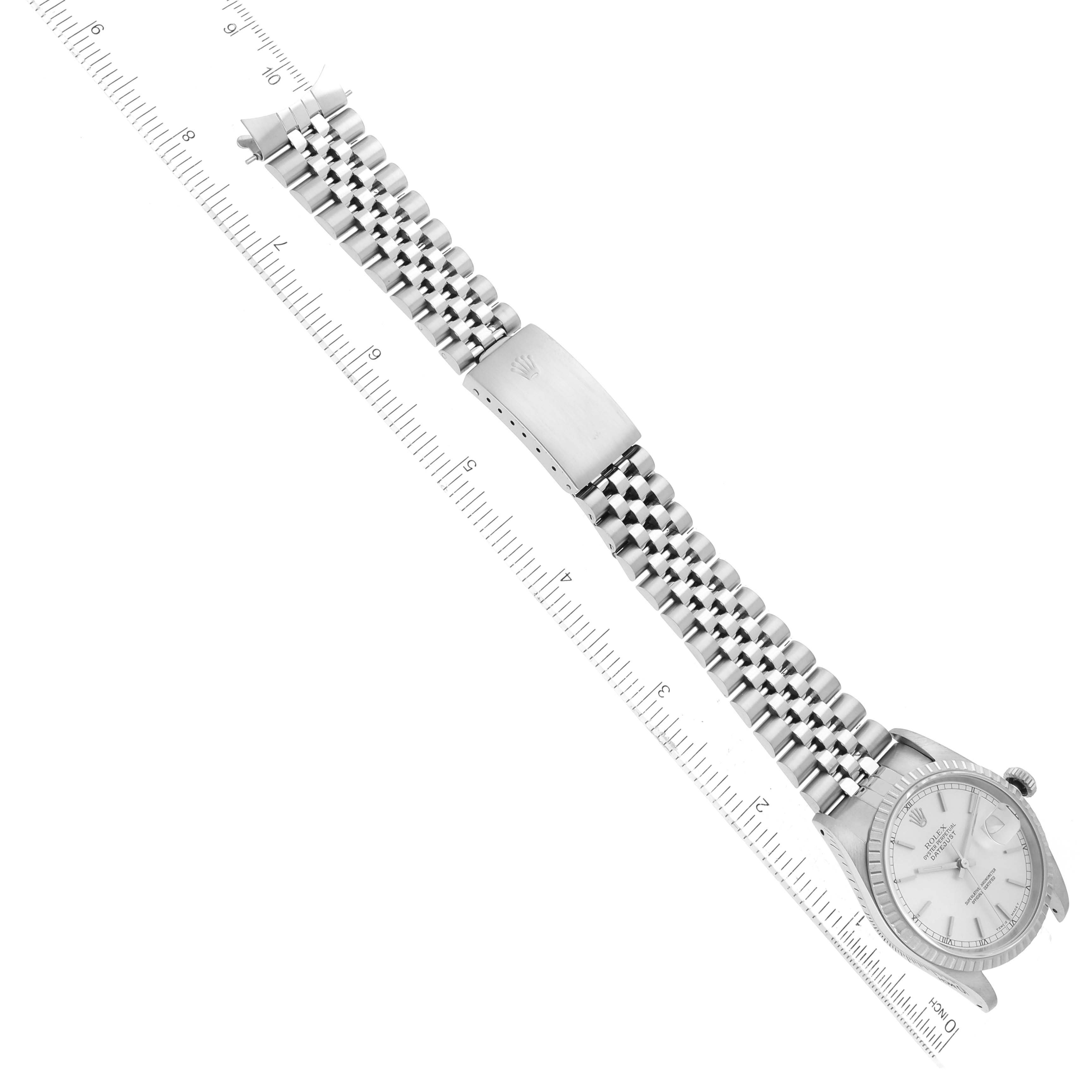 The Rolex Datejust 16220 Men's Stainless Steel Silver Dial 16220 Men's Stainless Steel Silver Dial watch is shown from a top-down angle, displaying the dial, bracelet, and clasp against a measuring ruler.