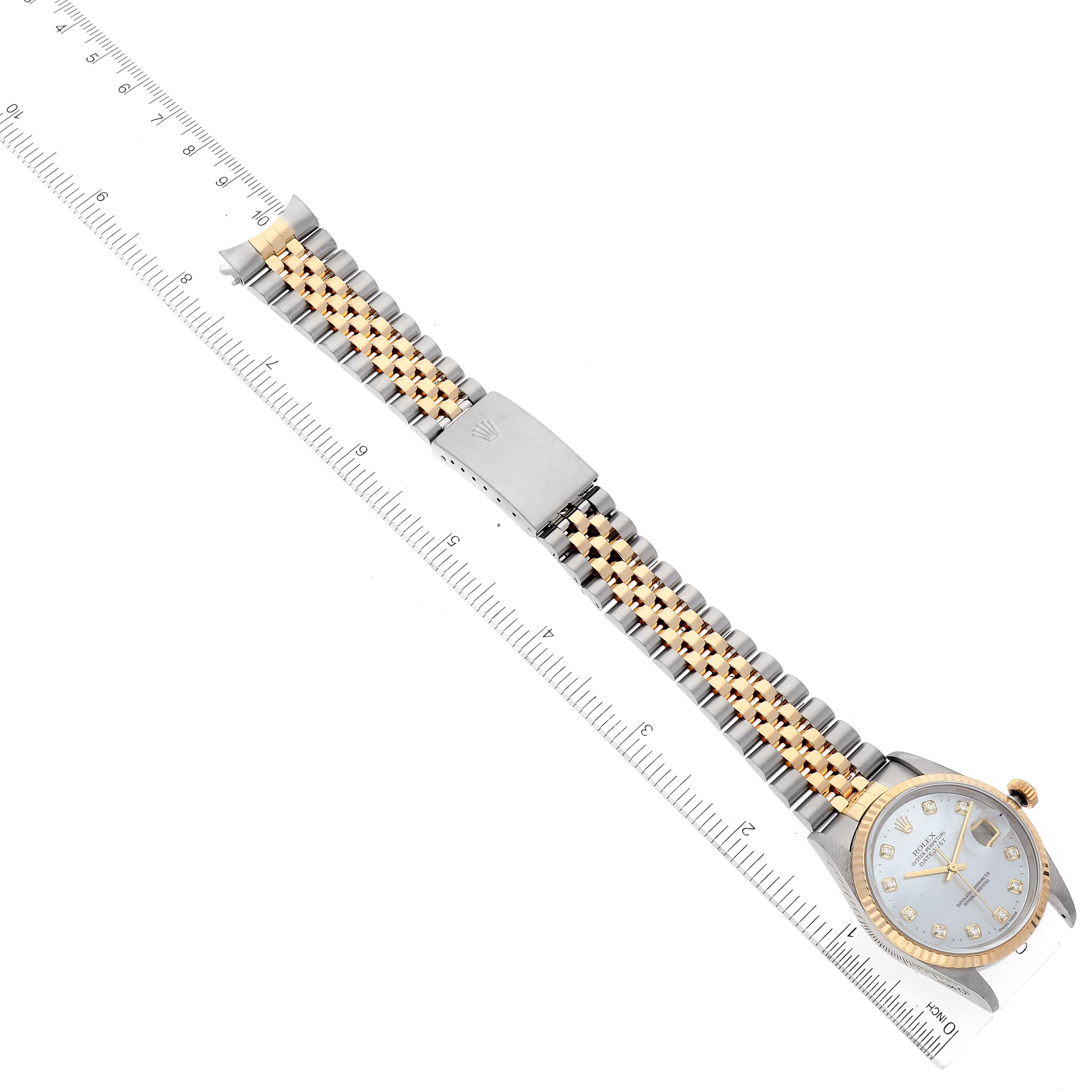 The image shows a Rolex Datejust 16233 Men's Steel and Gold (two tone) Mother of Pearl Dial 16233 Men's Steel and Gold (two tone) Mother of Pearl Dial watch laid flat, featuring its bracelet, clasp, and face alongside a ruler for measurement.