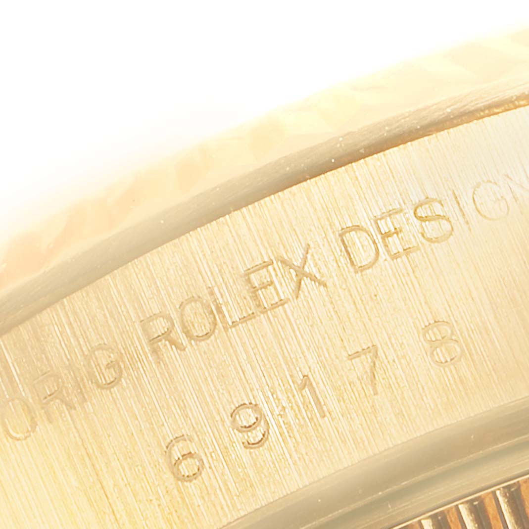 The image shows a close-up of the engraved bezel of a Rolex President 69178 Women's Yellow Gold Beige Dial 69178 Women's Yellow Gold Beige Dial model watch.