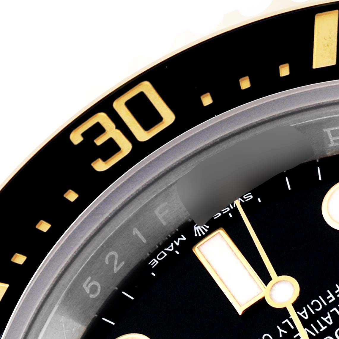 This close-up image of a Rolex Sea-Dweller 126603 Men
s Steel and Gold (two tone) Black Dial 126603 Men
s Steel and Gold (two tone) Black Dial watch shows the bezel, part of the dial, and indices.