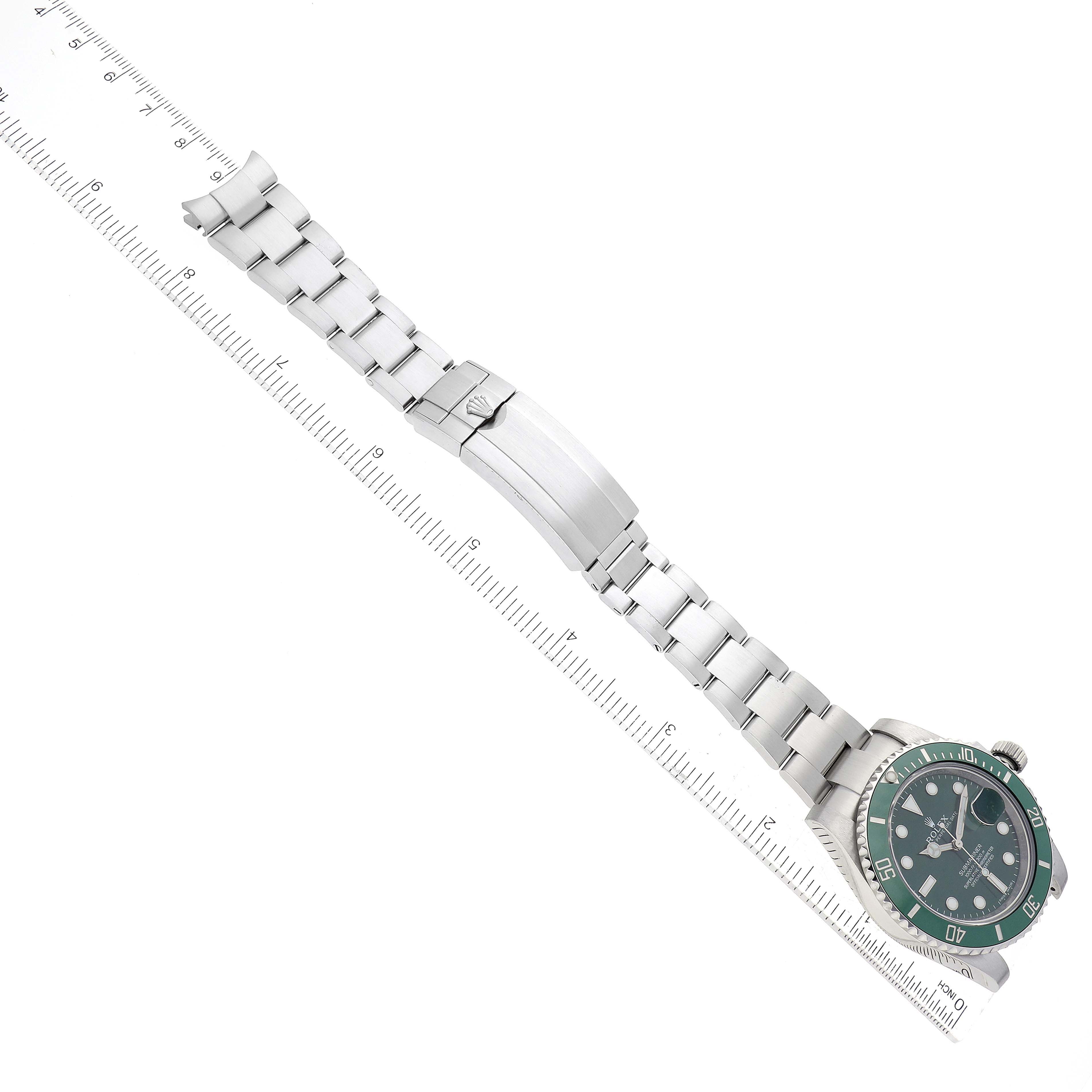 The Rolex Submariner 116610LV Men's Stainless Steel Green Dial 116610LV Men's Stainless Steel Green Dial watch is shown laid flat with its bracelet fully extended and positioned alongside a measuring ruler.
