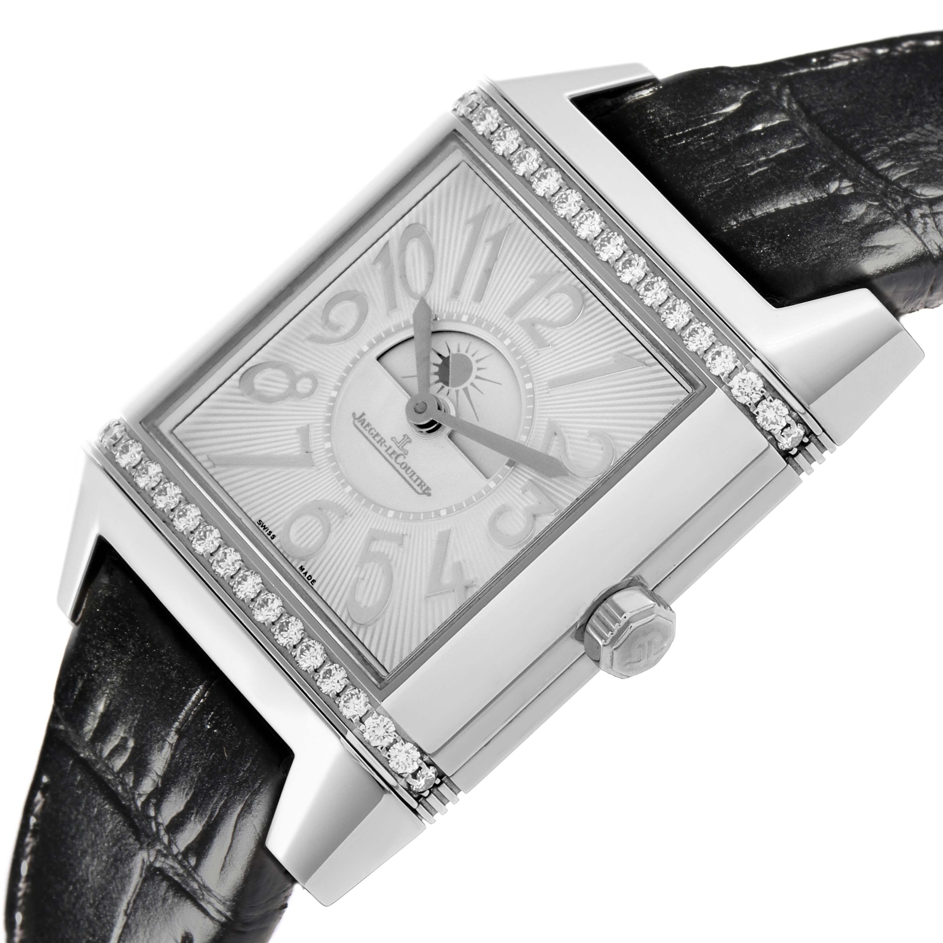 The Jaeger-LeCoultre Reverso watch is angled slightly to display its rectangular face, diamond-set bezel, and black strap.