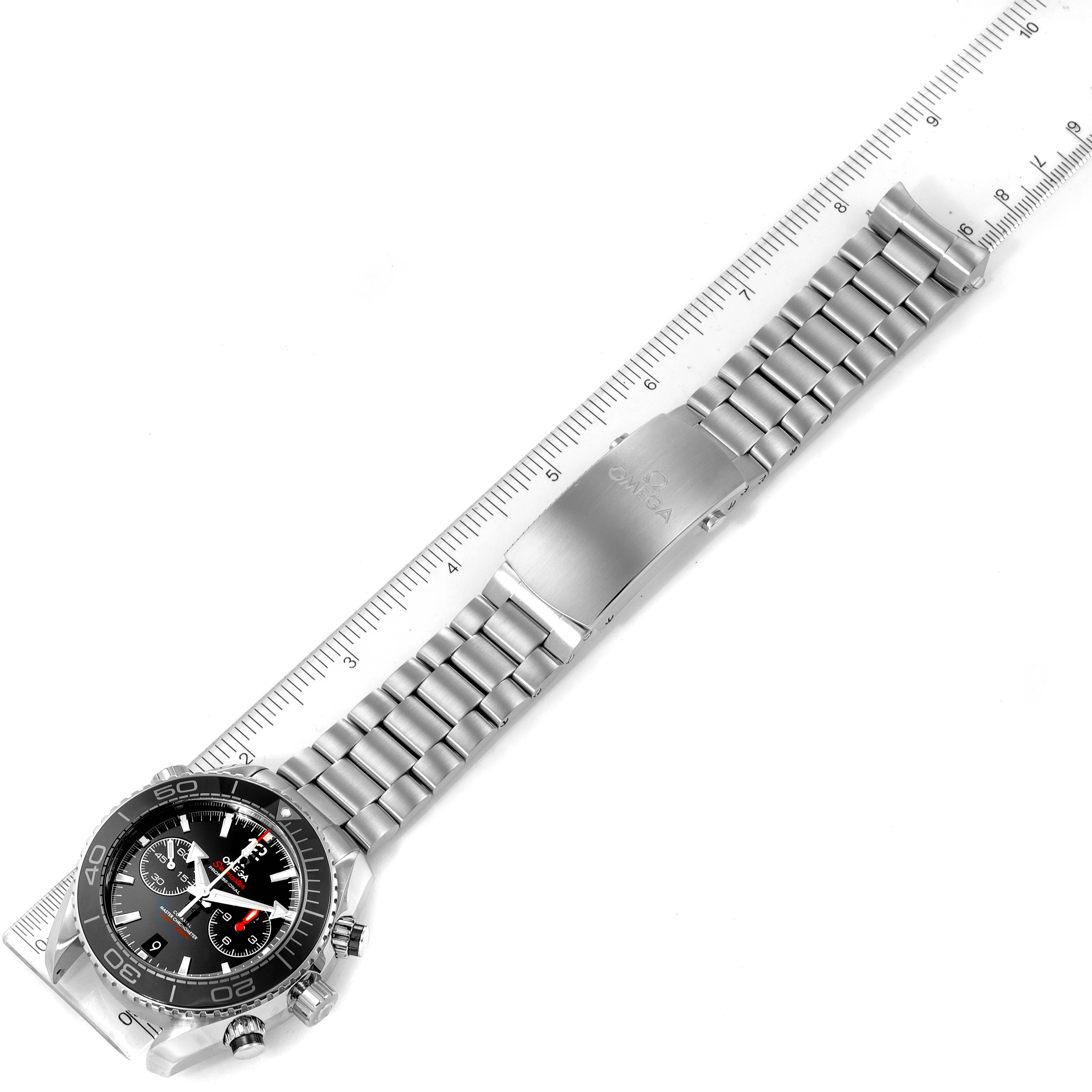 The Omega Planet Ocean 215.30.46.51.01.001 Men
s Stainless Steel Black Dial 215.30.46.51.01.001 Men
s Stainless Steel Black Dial watch is shown from a top-down angle, featuring the full bracelet and clasp extended alongside a ruler.