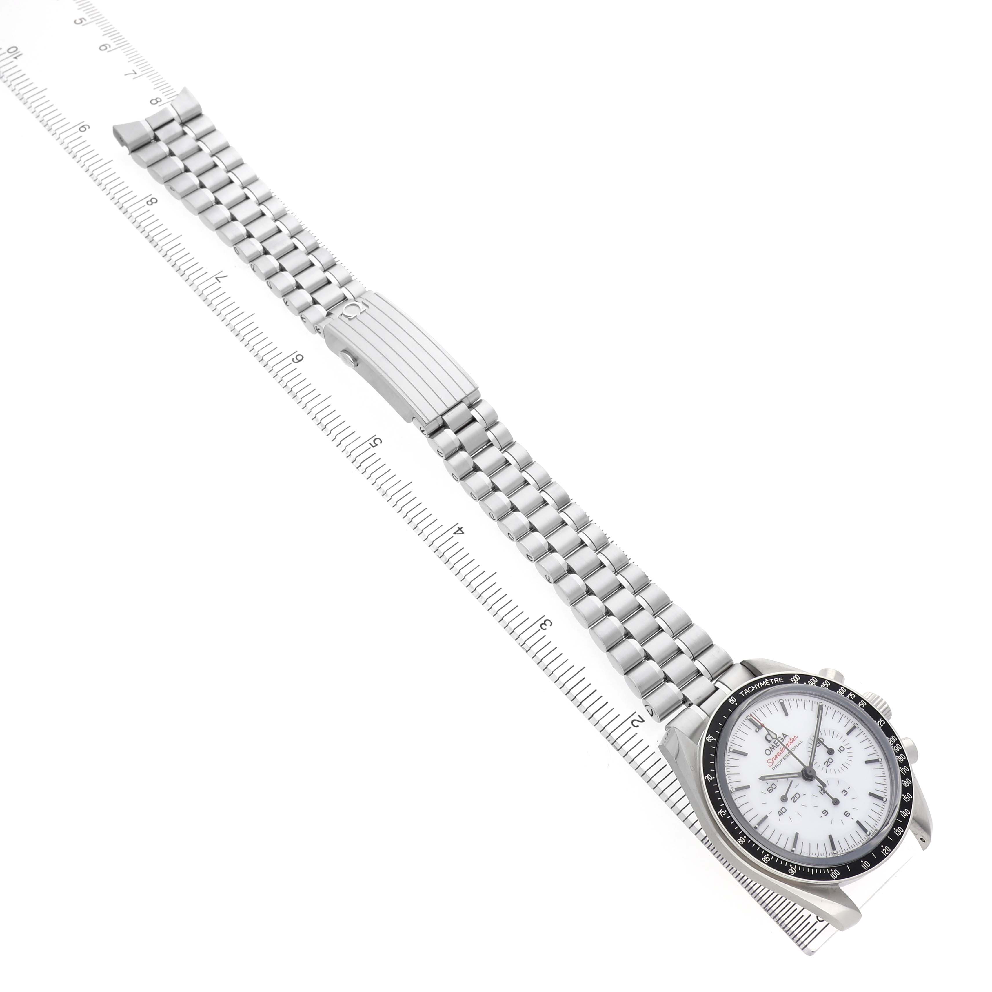 The Omega Speedmaster 310.30.42.50.04.001 Men's Stainless Steel White Dial watch is shown at an angled view with its full stainless steel bracelet and clasp visible alongside a ruler.