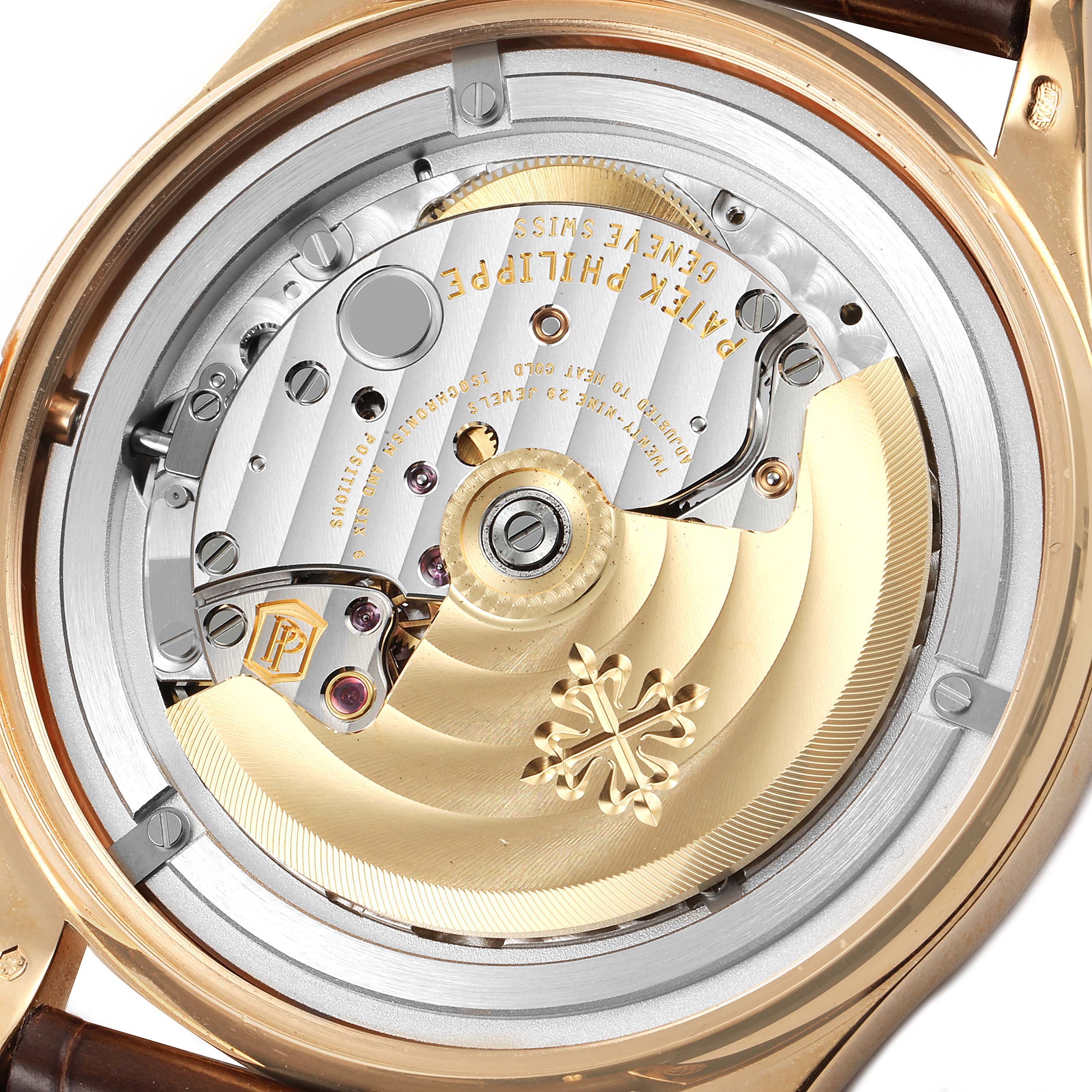 The image shows the exposed case back and movement of a Patek Philippe Calatrava 5296R-010 Men
s Rose Gold Silver Dial 5296R-010 Men
s Rose Gold Silver Dial watch, highlighting its intricate mechanics.