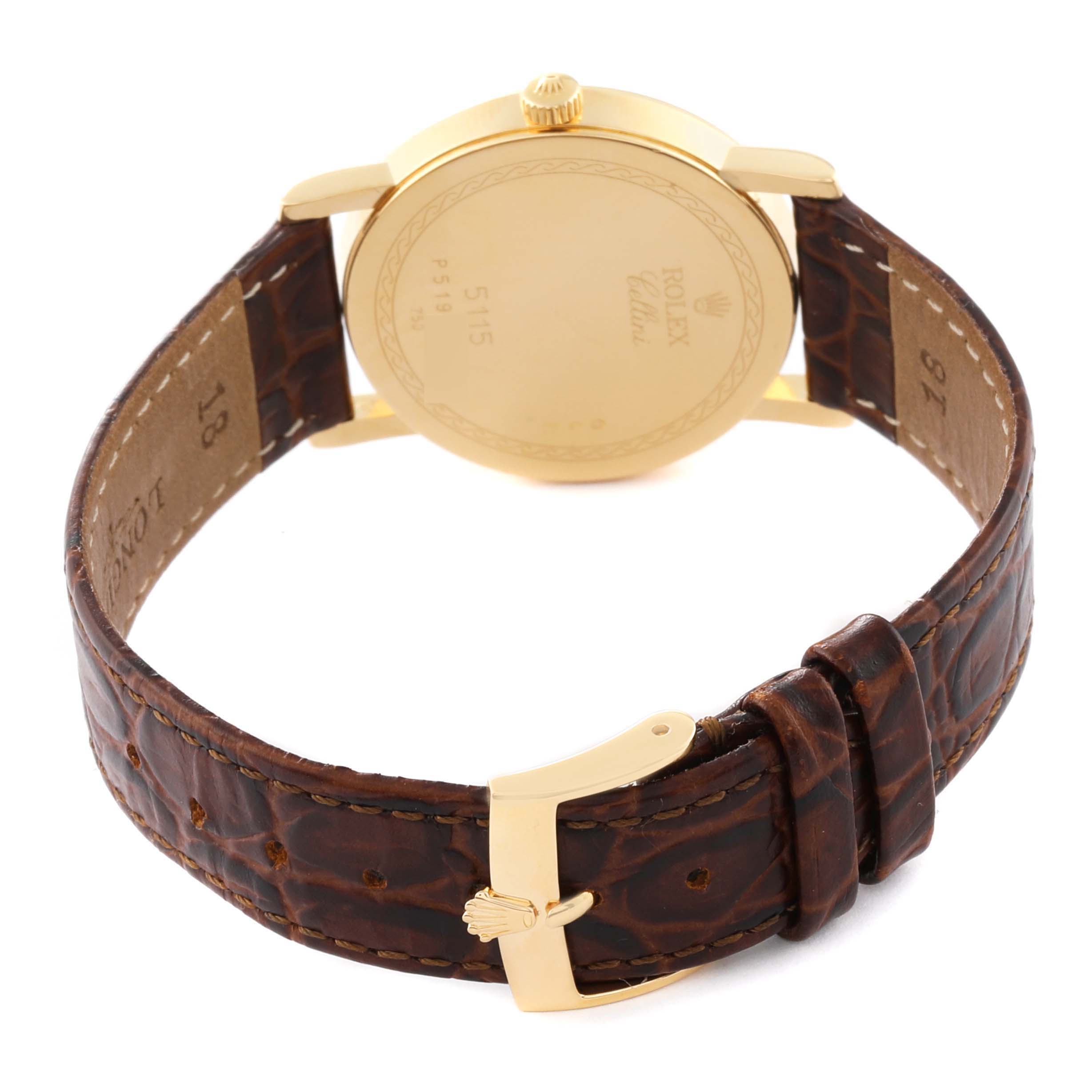 The image shows the back view of a Rolex Cellini 5115/8 Men's Yellow Gold Champagne Dial 5115/8 Men's Yellow Gold Champagne Dial watch, featuring its gold case, crown, and brown leather strap with a gold buckle.