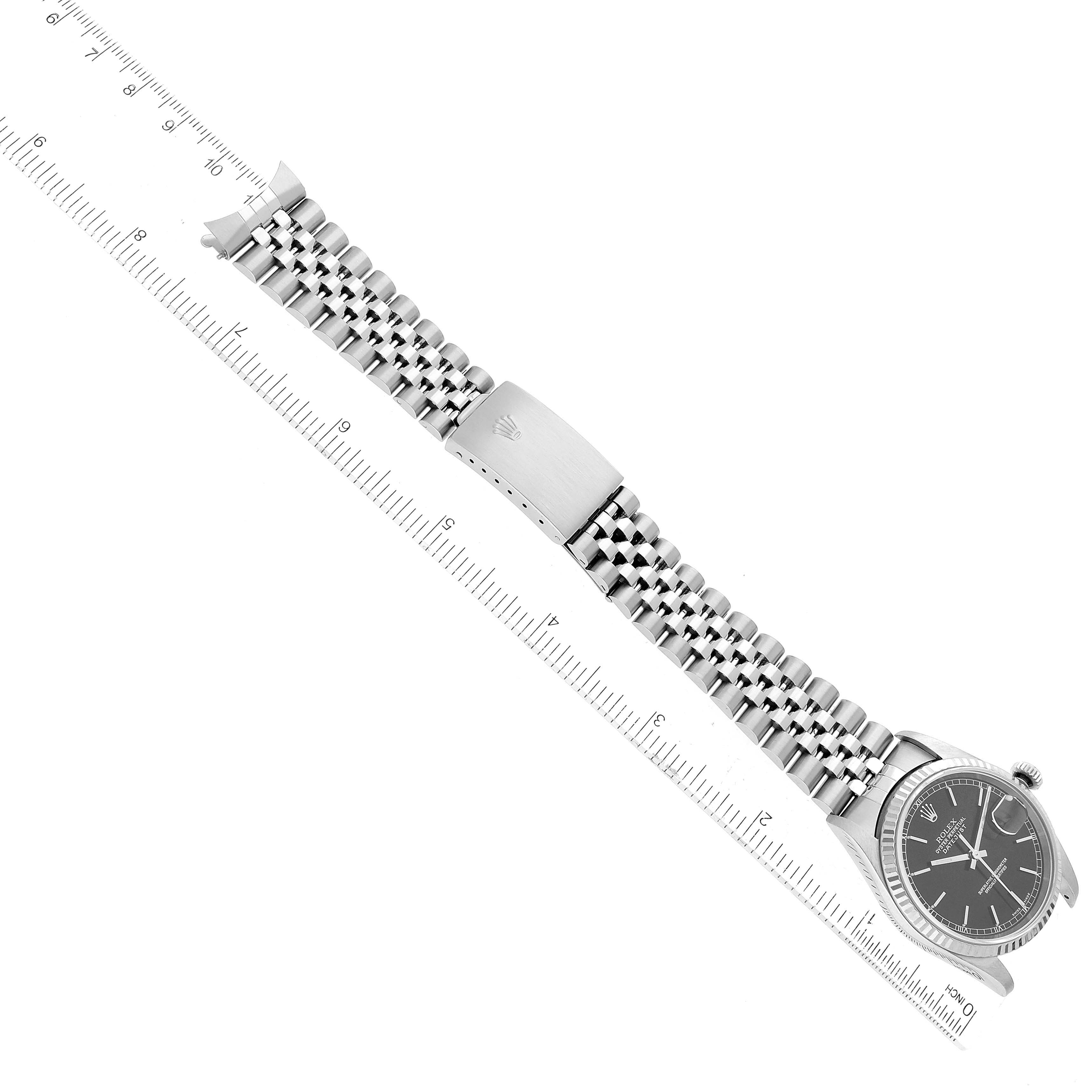 The image shows a Rolex Datejust 16234 Men's Stainless Steel Black Dial 16234 Men's Stainless Steel Black Dial watch laid flat, displaying the dial, Jubilee bracelet, and clasp, with a ruler for scale.