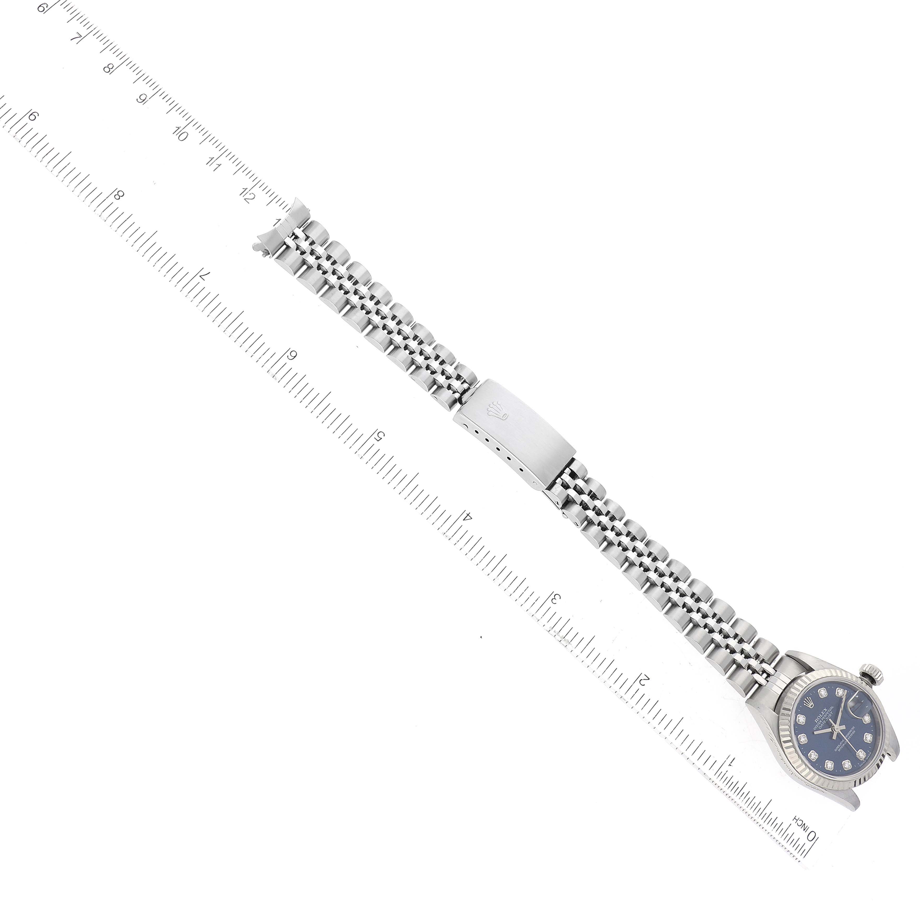 The image shows a Rolex Datejust 79174 Women's Stainless Steel Blue Dial 79174 Women's Stainless Steel Blue Dial watch laid horizontally beside a ruler, displaying its bracelet, clasp, and dial.