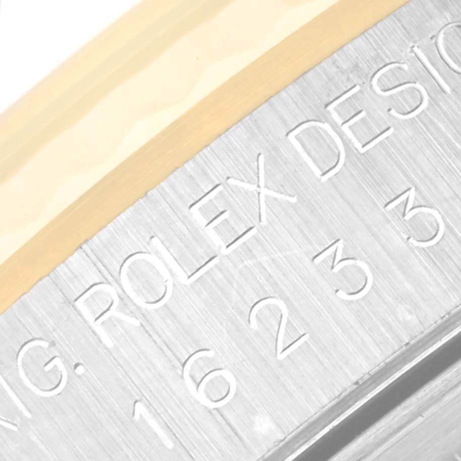 This close-up image shows the engraved serial number and "Rolex Design" text on the casing of a Rolex Datejust 16233 Men's Steel and Gold (two tone) Champagne Dial 16233 Men's Steel and Gold (two tone) Champagne Dial watch.
