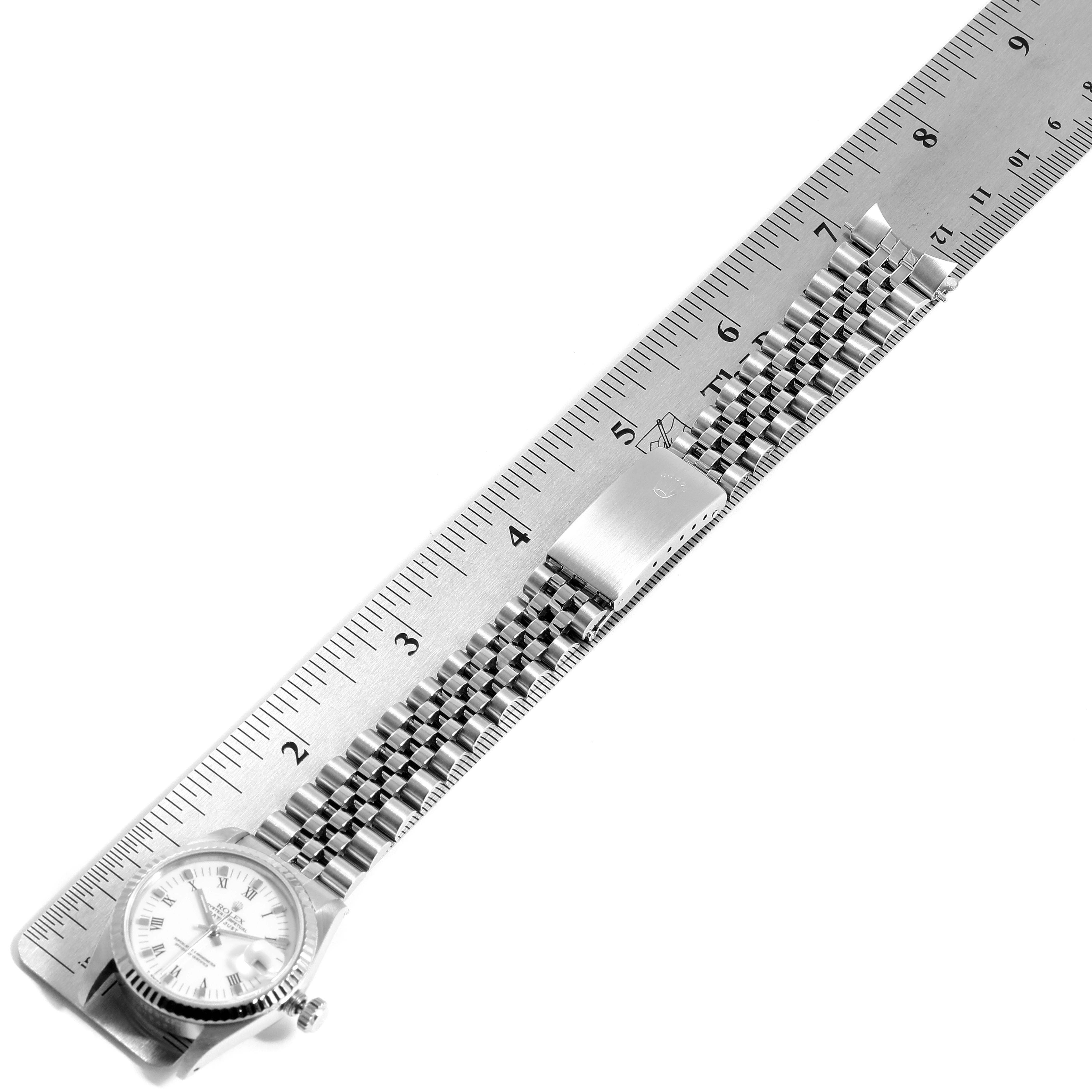 The image shows a Mid-Size Rolex watch placed next to a ruler, displaying the face and metal bracelet.