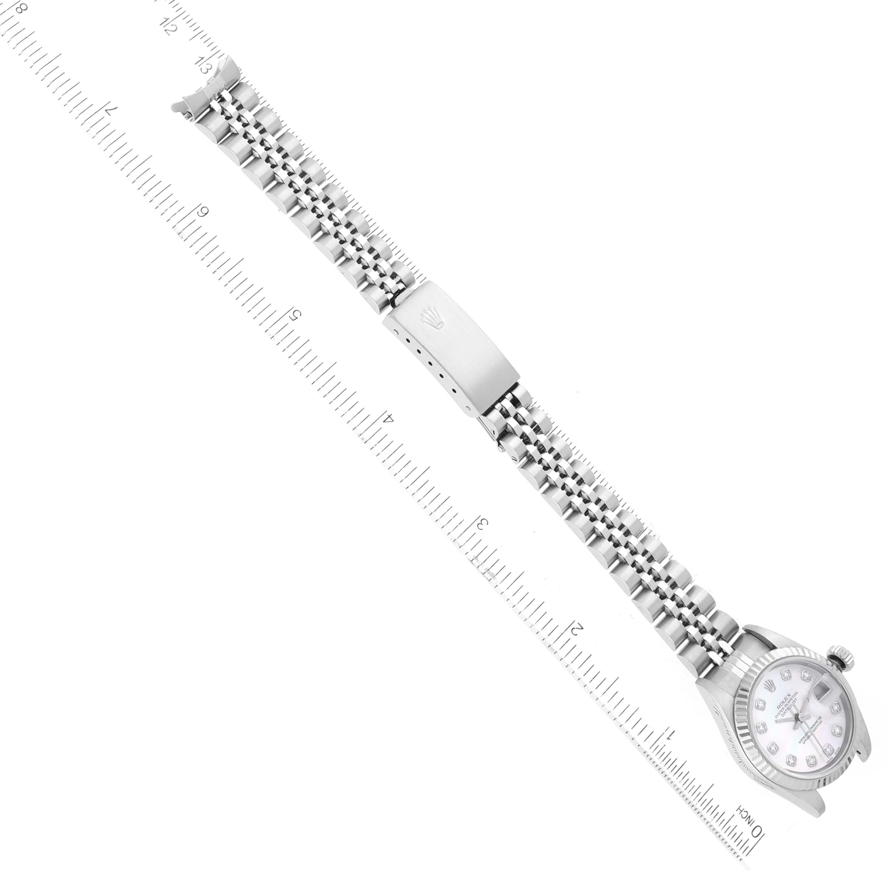 The image shows a top-down view of a Rolex Datejust 79174 Women
s Stainless Steel Mother of Pearl Dial 79174 Women
s Stainless Steel Mother of Pearl Dial watch, highlighting the face, bracelet, and clasp against a measuring ruler.