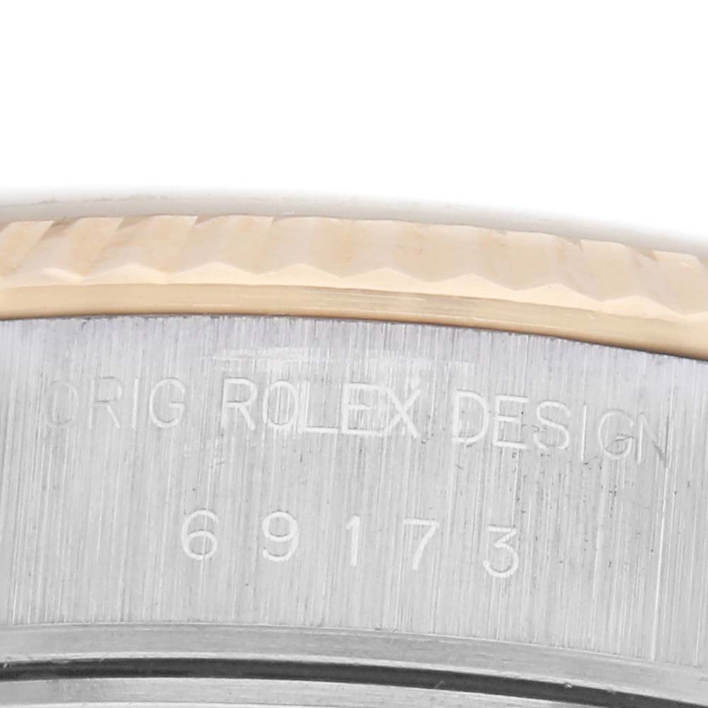 The image shows a close-up of the side of a Rolex Datejust 69173 Women
s Steel and Gold (two tone) Champagne Dial 69173 Women
s Steel and Gold (two tone) Champagne Dial, highlighting the bezel and engraved serial/design number.