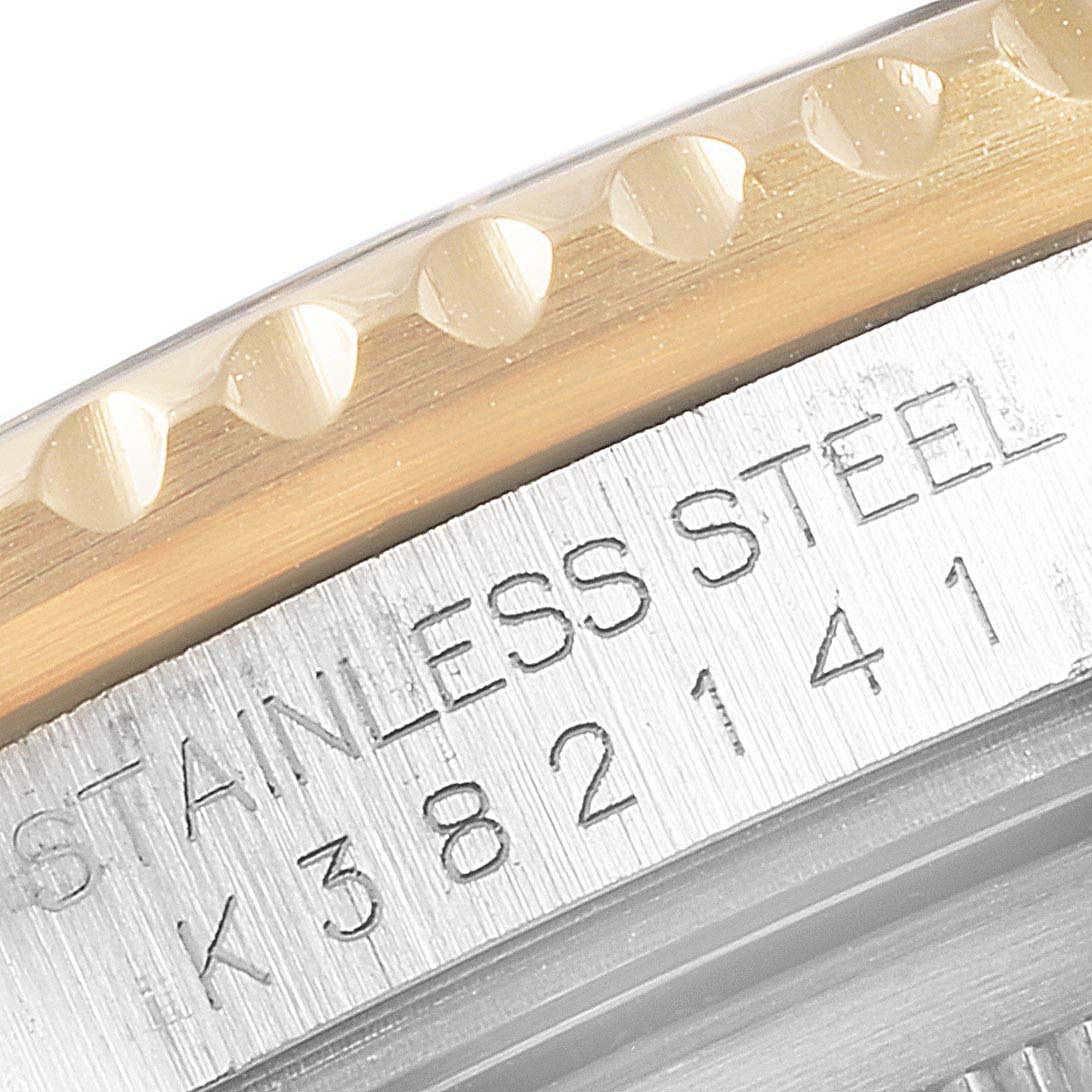 This close-up image of the Rolex GMT-Master 16713  Men's Steel and Gold (two tone) Black Dial 16713  Men's Steel and Gold (two tone) Black Dial watch shows the engraved serial number, "STAINLESS STEEL," and the edge of the bezel.