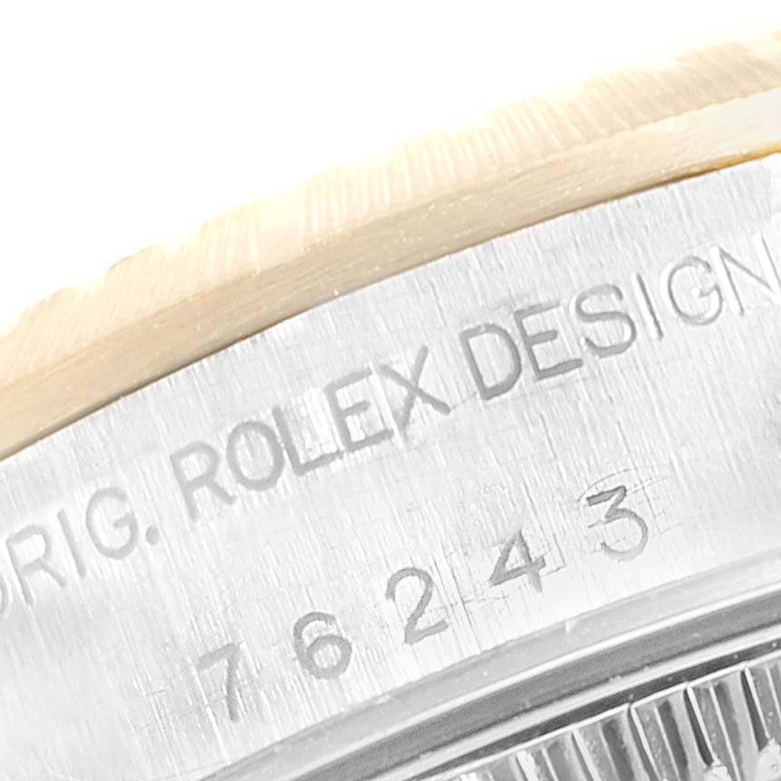 The image shows a close-up of the case and bezel of a Rolex Oyster Perpetual 76243 Women
s Steel and Gold (two tone) Champagne Dial 76243 Women
s Steel and Gold (two tone) Champagne Dial watch, highlighting the engraved design and model number.