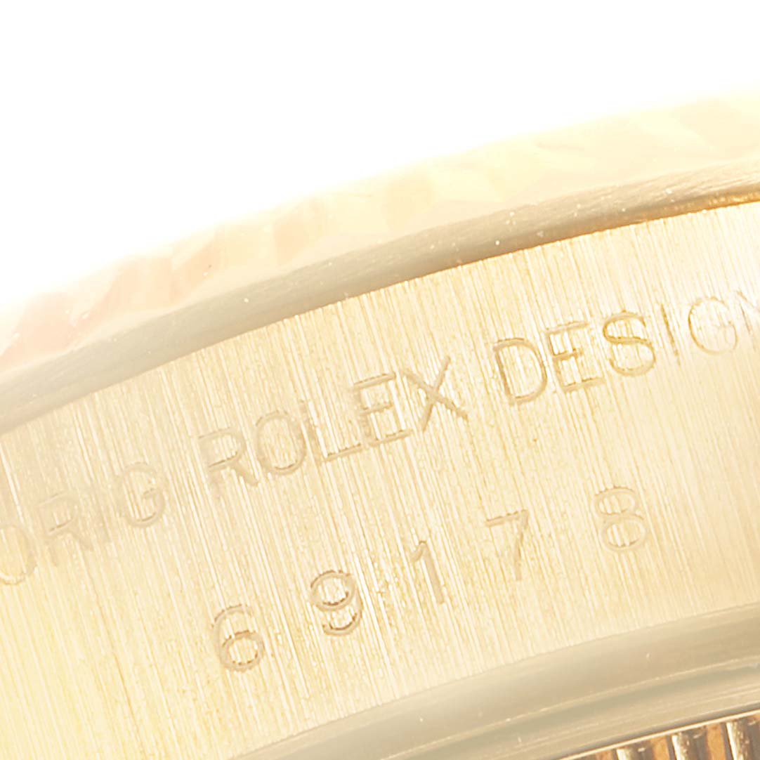 The image shows a close-up angle of the side of a Rolex President 79178 Women
s Yellow Gold Champagne Dial 79178 Women
s Yellow Gold Champagne Dial watch case, focusing on engraved text and details.