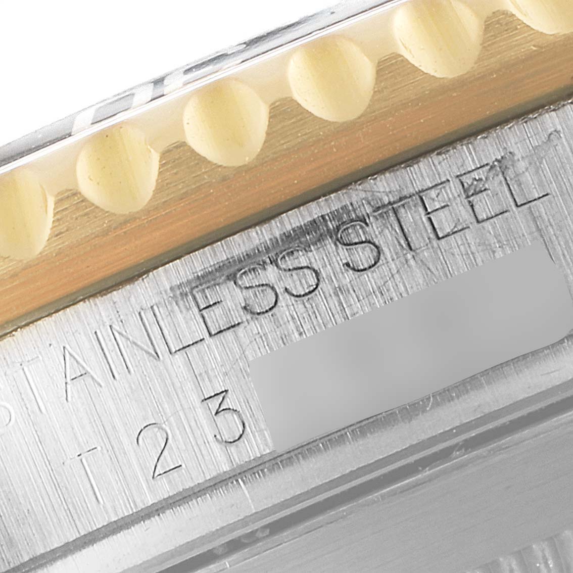 This is a close-up image of the Rolex Submariner 16613 Men's Steel and Gold (two tone) Black Dial 16613 Men's Steel and Gold (two tone) Black Dial's bezel and engraved stainless steel side case, including a portion of its serial number.