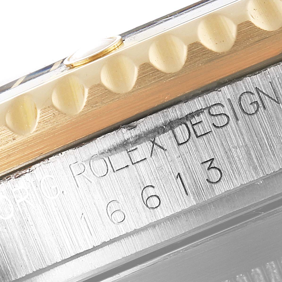 The image shows a close-up of the side of a Rolex Submariner 16613 Men's Steel and Gold (two tone) Black Dial 16613 Men's Steel and Gold (two tone) Black Dial watch, focusing on the serial number and edge of the bezel.