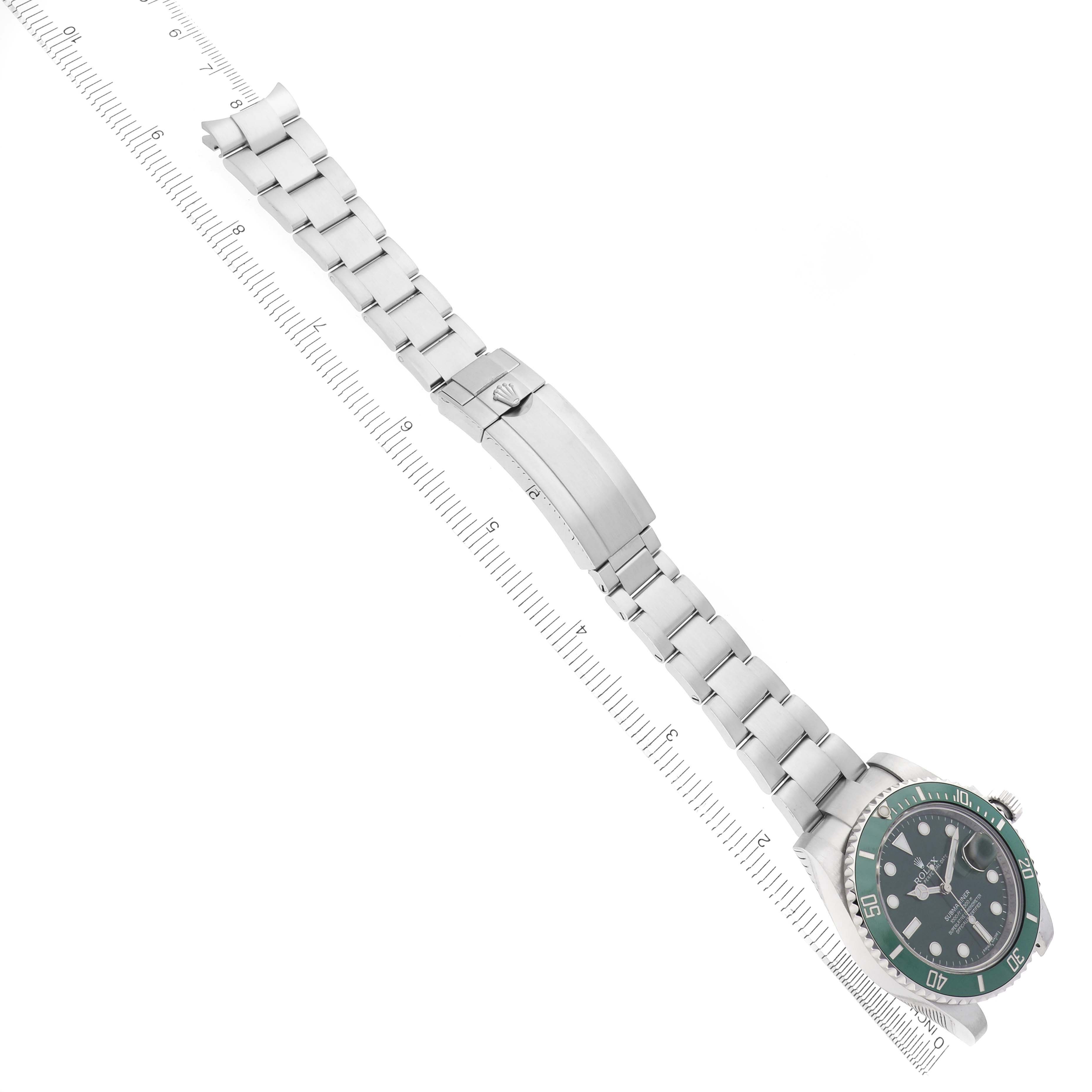 The image shows a Rolex Submariner 116610LV Men
s Stainless Steel Green Dial 116610LV Men
s Stainless Steel Green Dial watch laid down with a full view of the bracelet and case, positioned diagonally with a ruler.
