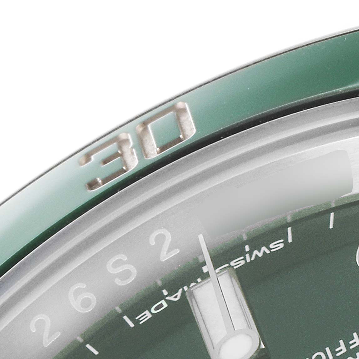 The image shows a close-up of the bezel and part of the dial of a green Rolex Submariner 116610LV Men
s Stainless Steel Green Dial 116610LV Men
s Stainless Steel Green Dial.