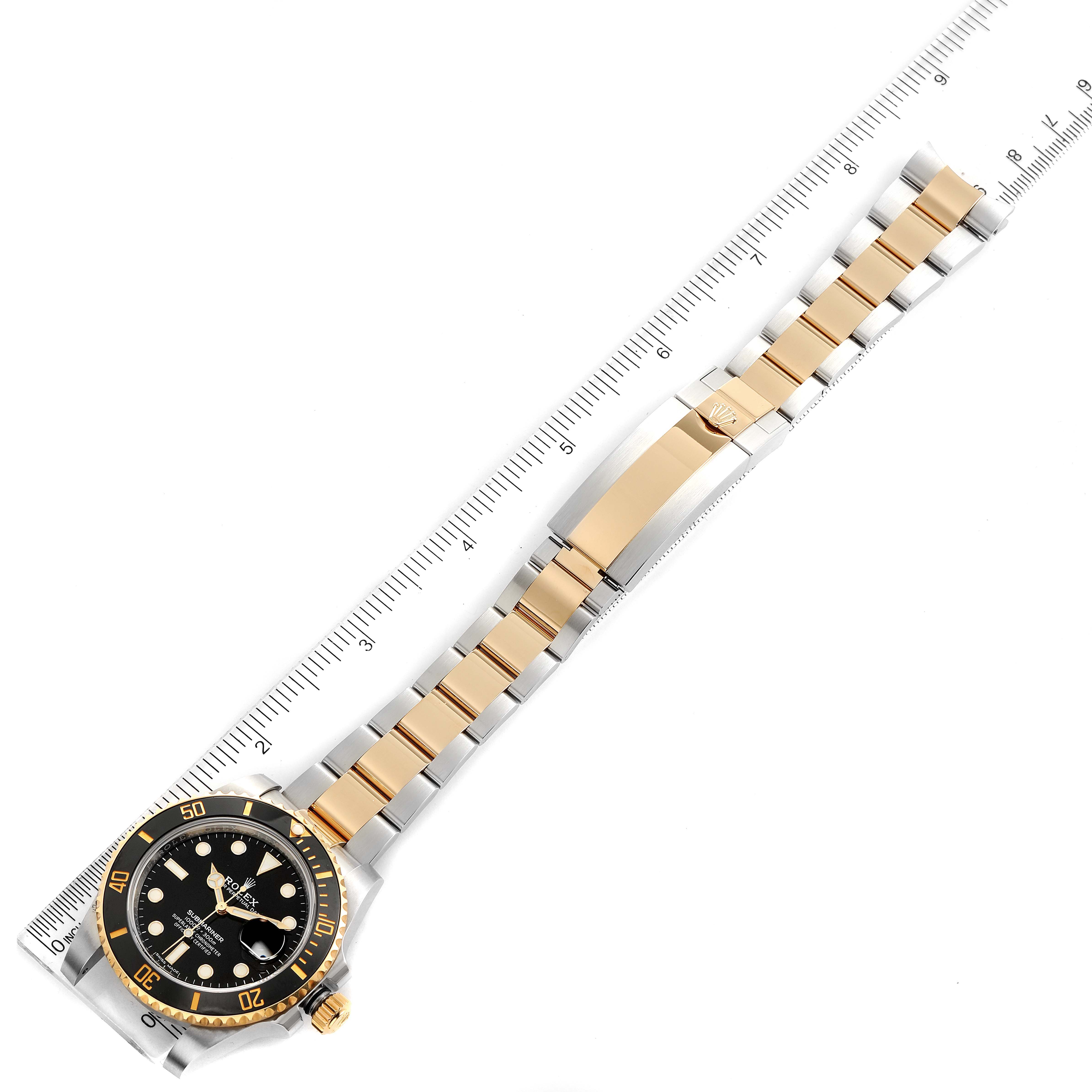 The image shows a top view of a Rolex Submariner 116613 Men
s Steel and Gold (two tone) Black Dial 116613 Men
s Steel and Gold (two tone) Black Dial watch, including the face, bezel, and full bracelet next to a ruler for measurement.