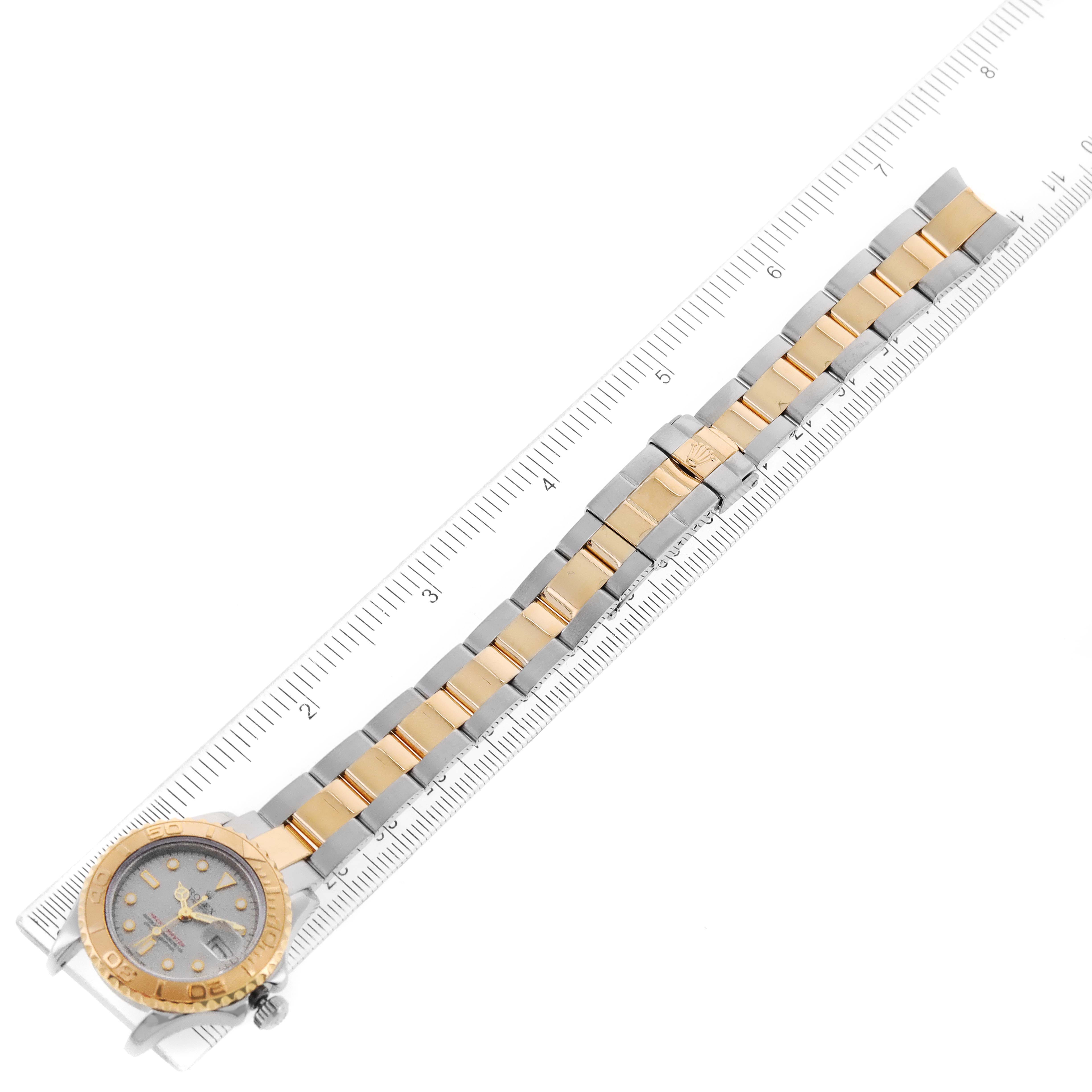 The Rolex Yacht-Master 69623 Women's Steel and Gold (two tone) Grey Dial 69623 Women's Steel and Gold (two tone) Grey Dial watch is shown flat from above, with a clear view of the band and face, placed adjacent to a ruler.