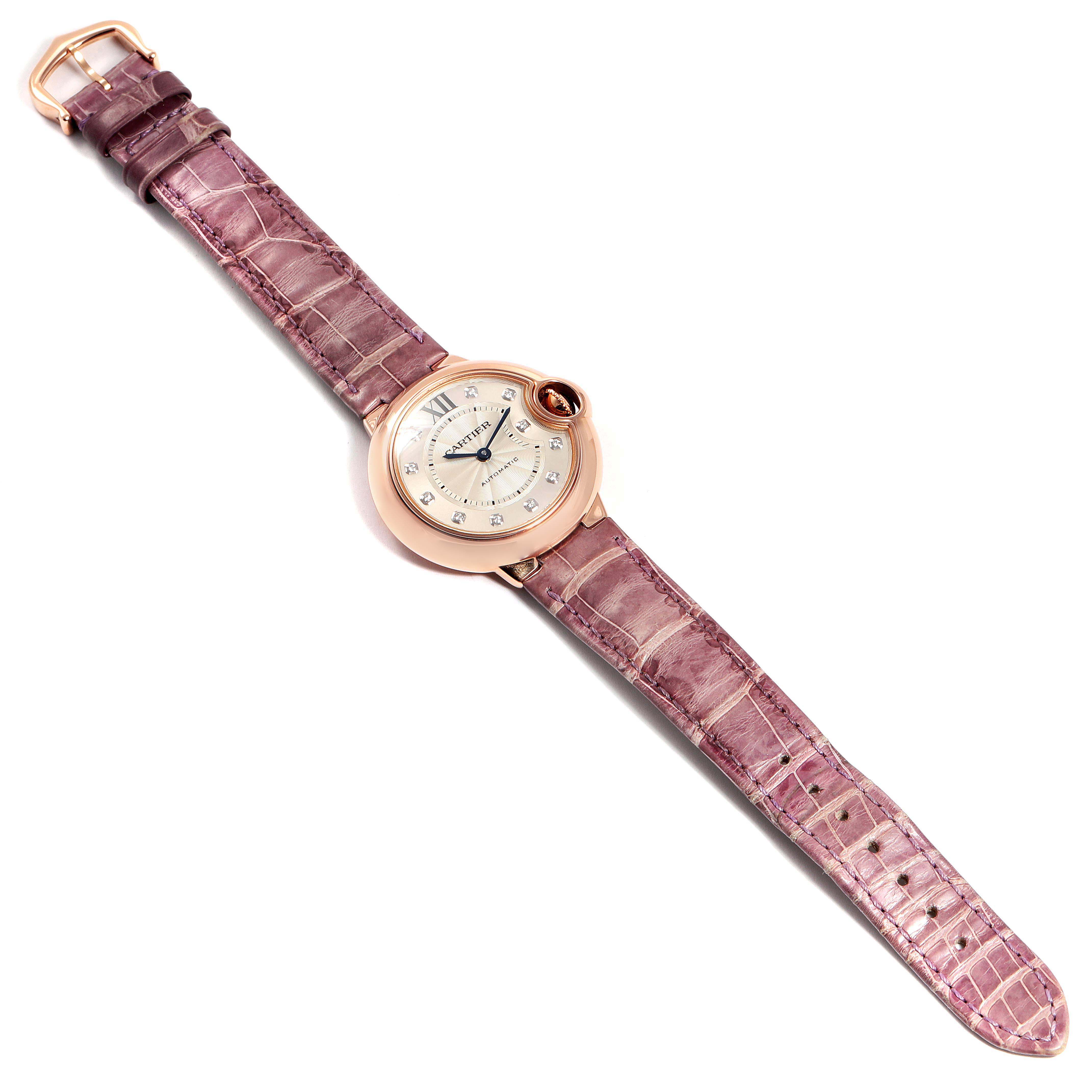 The Cartier Ballon Bleu WE902063 Women's Rose Gold Silver Dial WE902063 Women's Rose Gold Silver Dial watch is shown from an overhead angle, displaying its pink leather strap and round dial with Roman numerals.