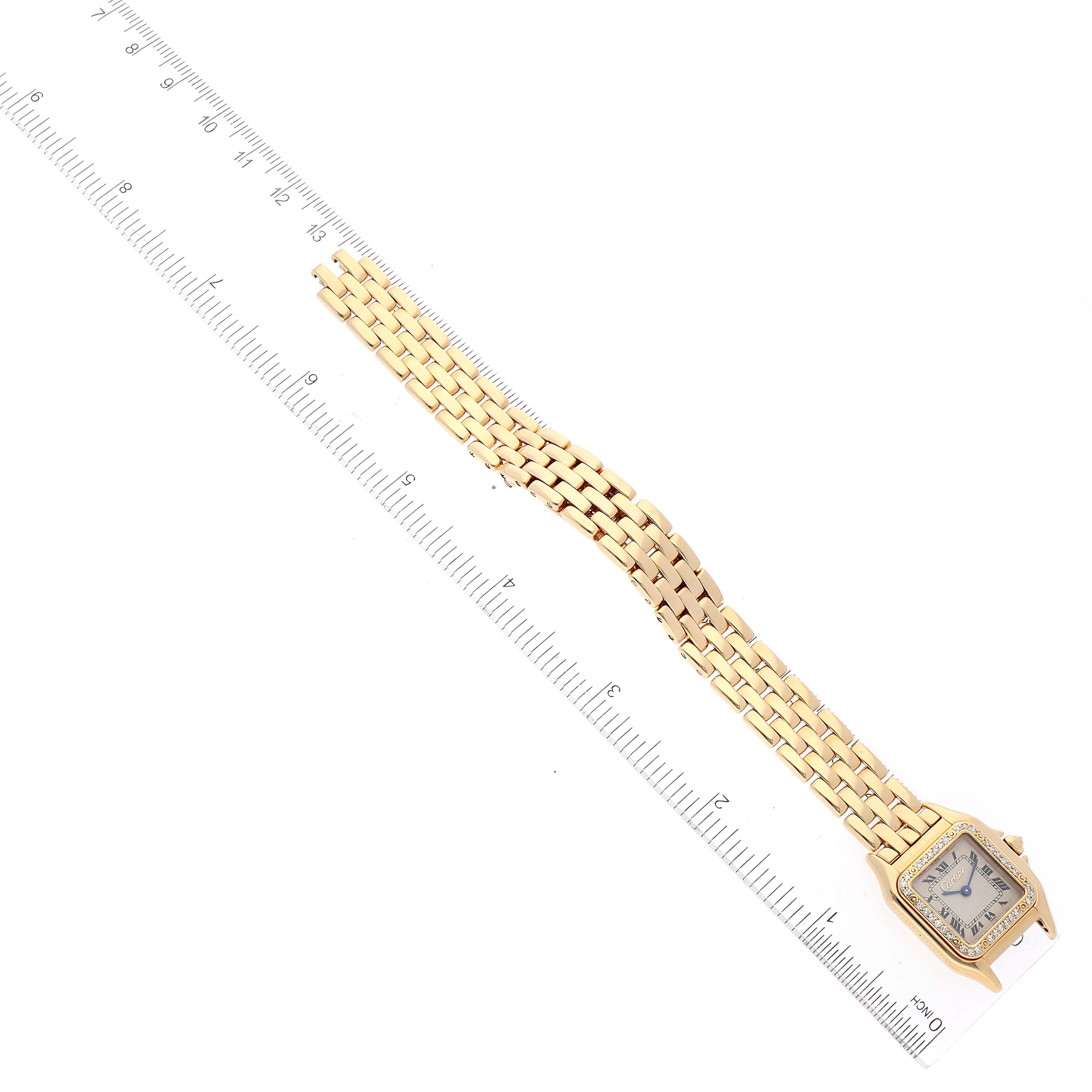 The image shows the top view of a Cartier Panthere Women's Yellow Gold Silver Dial Women's Yellow Gold Silver Dial watch laid alongside a ruler.