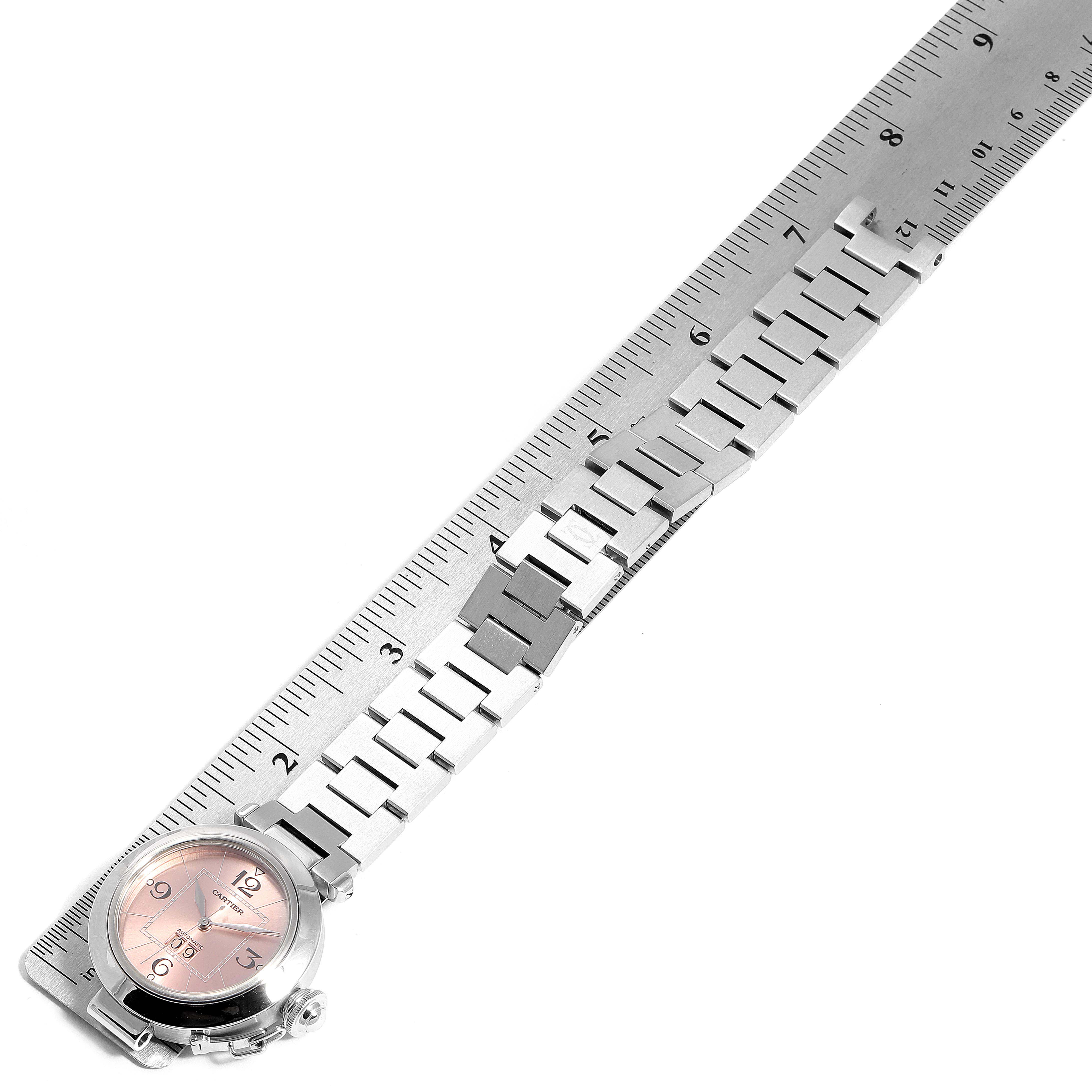 The image shows the Cartier Pasha W31058M7 Women's Stainless Steel Pink Dial W31058M7 Women's Stainless Steel Pink Dial watch placed alongside a ruler, highlighting its face and bracelet.