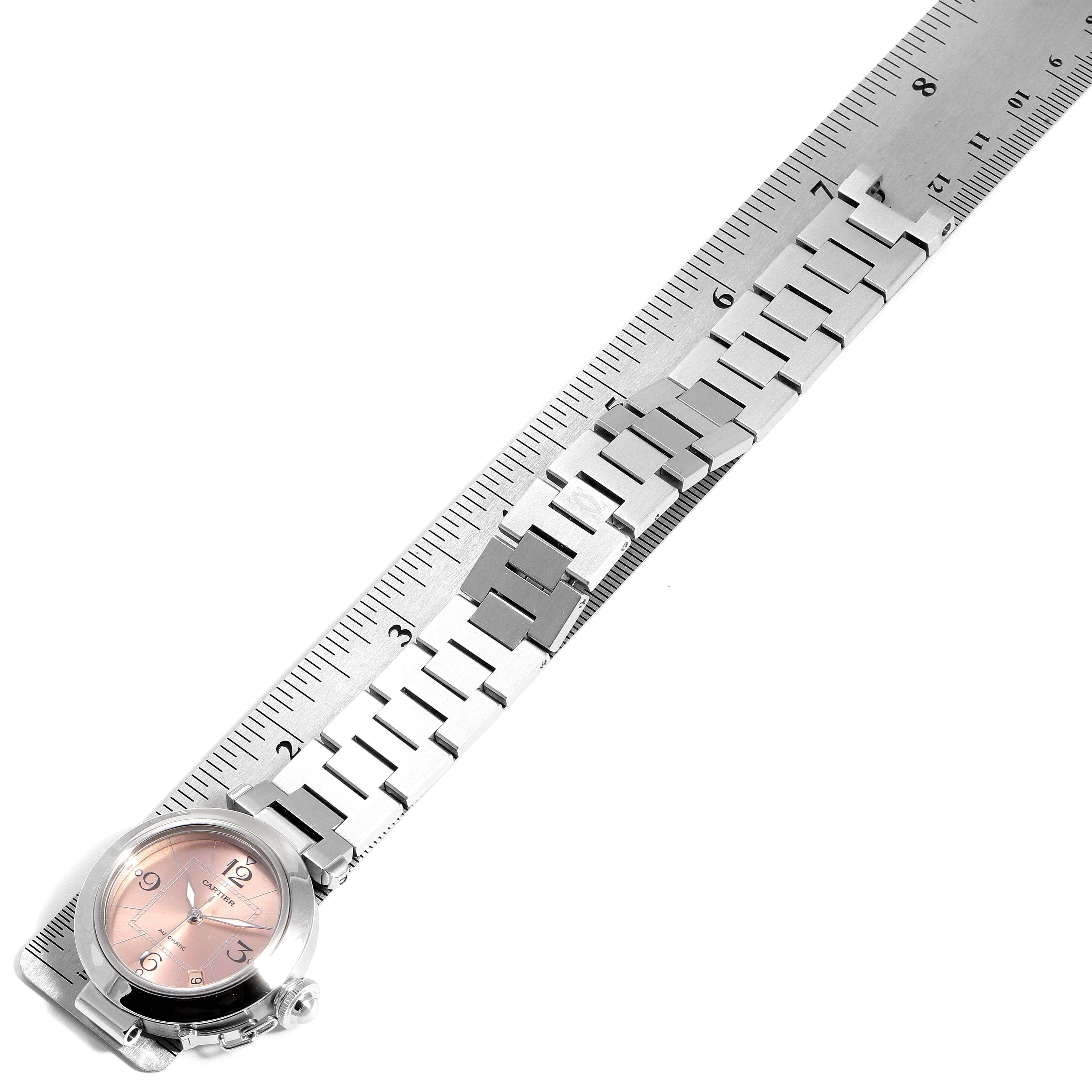 The image shows a Cartier Pasha W31075M7 Women's Stainless Steel Pink Dial W31075M7 Women's Stainless Steel Pink Dial model watch laid flat against a ruler, displaying the watch face and metal bracelet.