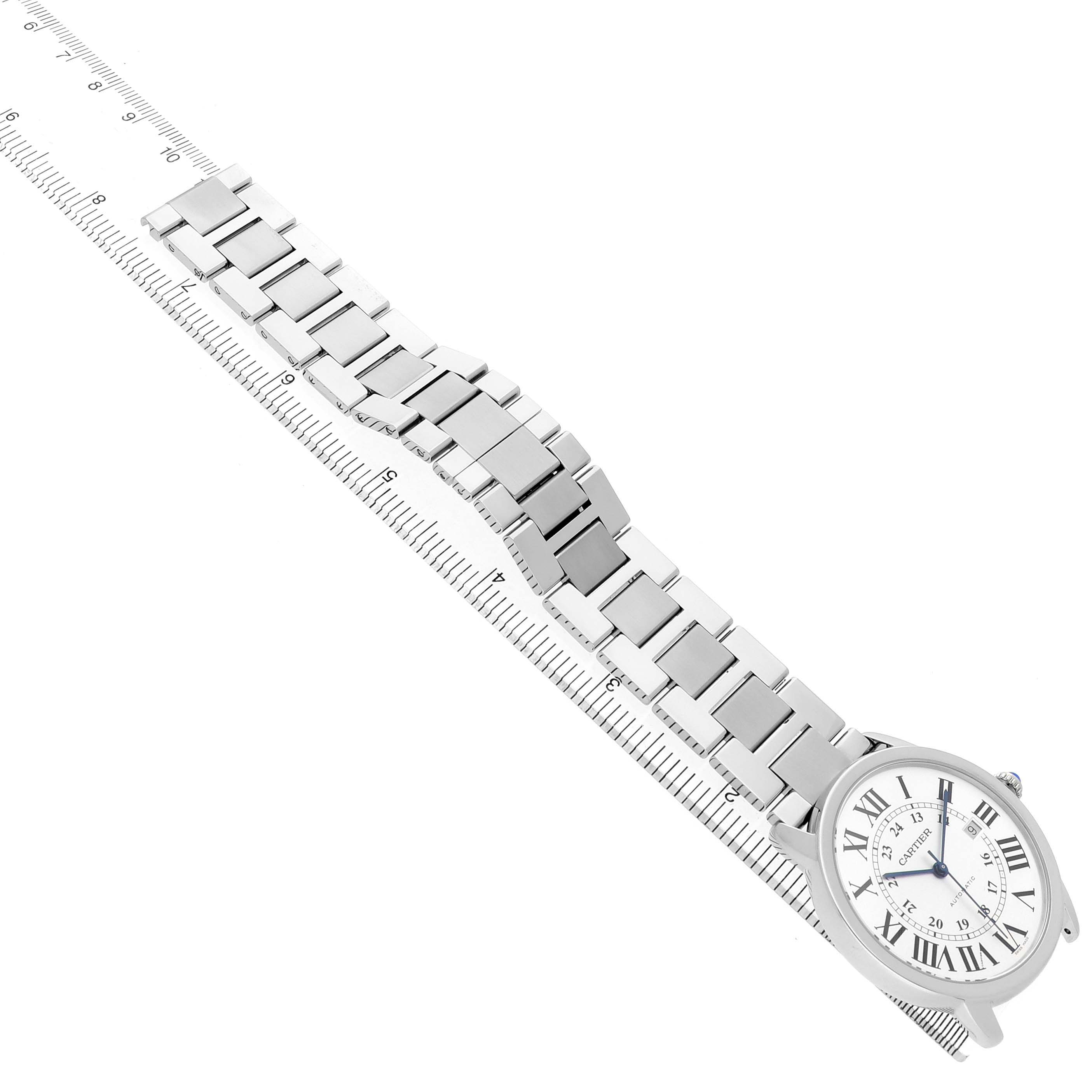 The Cartier Ronde W6701011 Men's Stainless Steel Silver Dial watch is shown from a top-down angle, displaying its face and entire metal bracelet laid along a ruler.