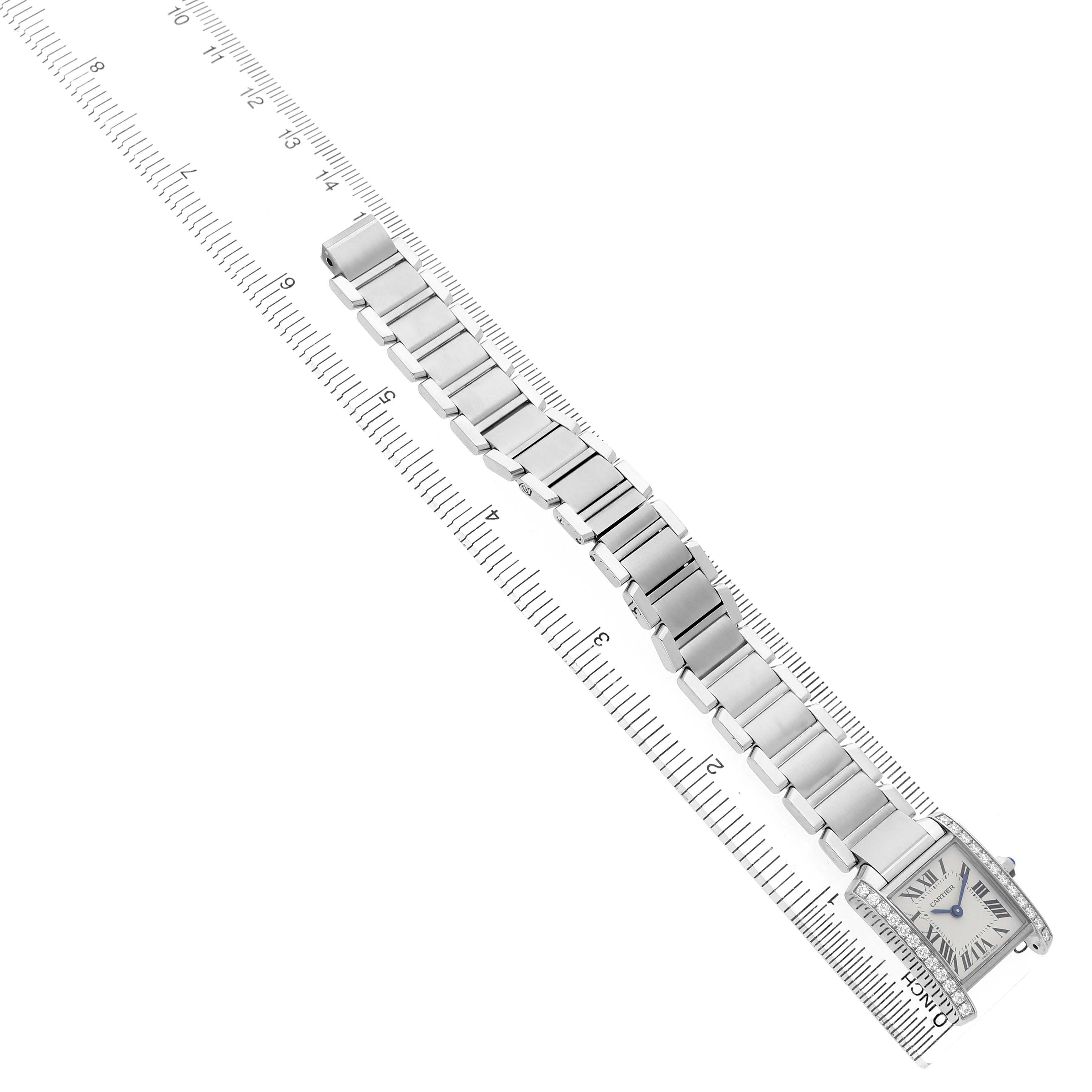 The Cartier Tank Française watch is shown from a top-down angle with its bracelet extended along a ruler.