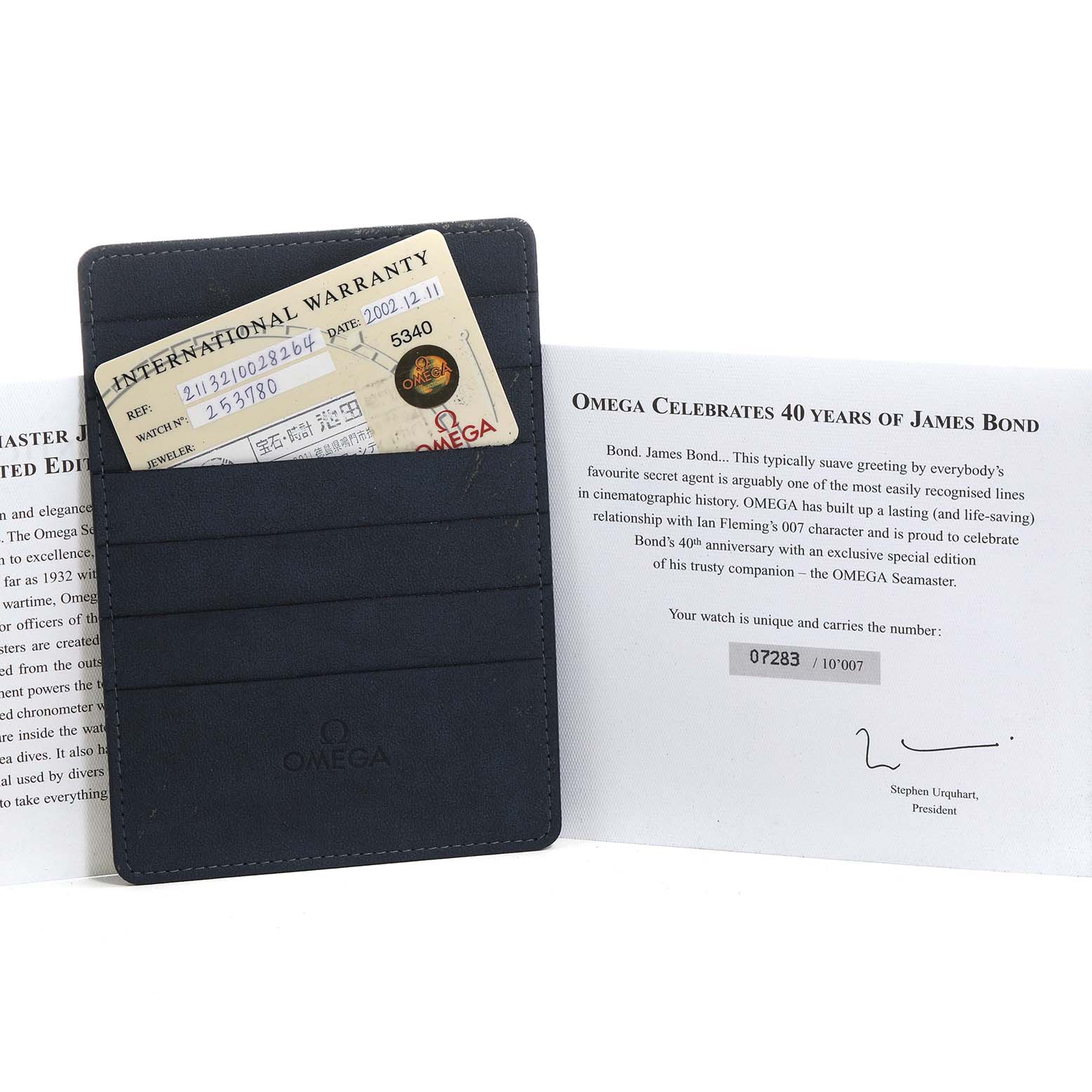 The image shows an Omega Seamaster 2537.80.00 Men's Stainless Steel Blue Dial warranty card in a wallet and a certificate celebrating James Bond's 40th anniversary.