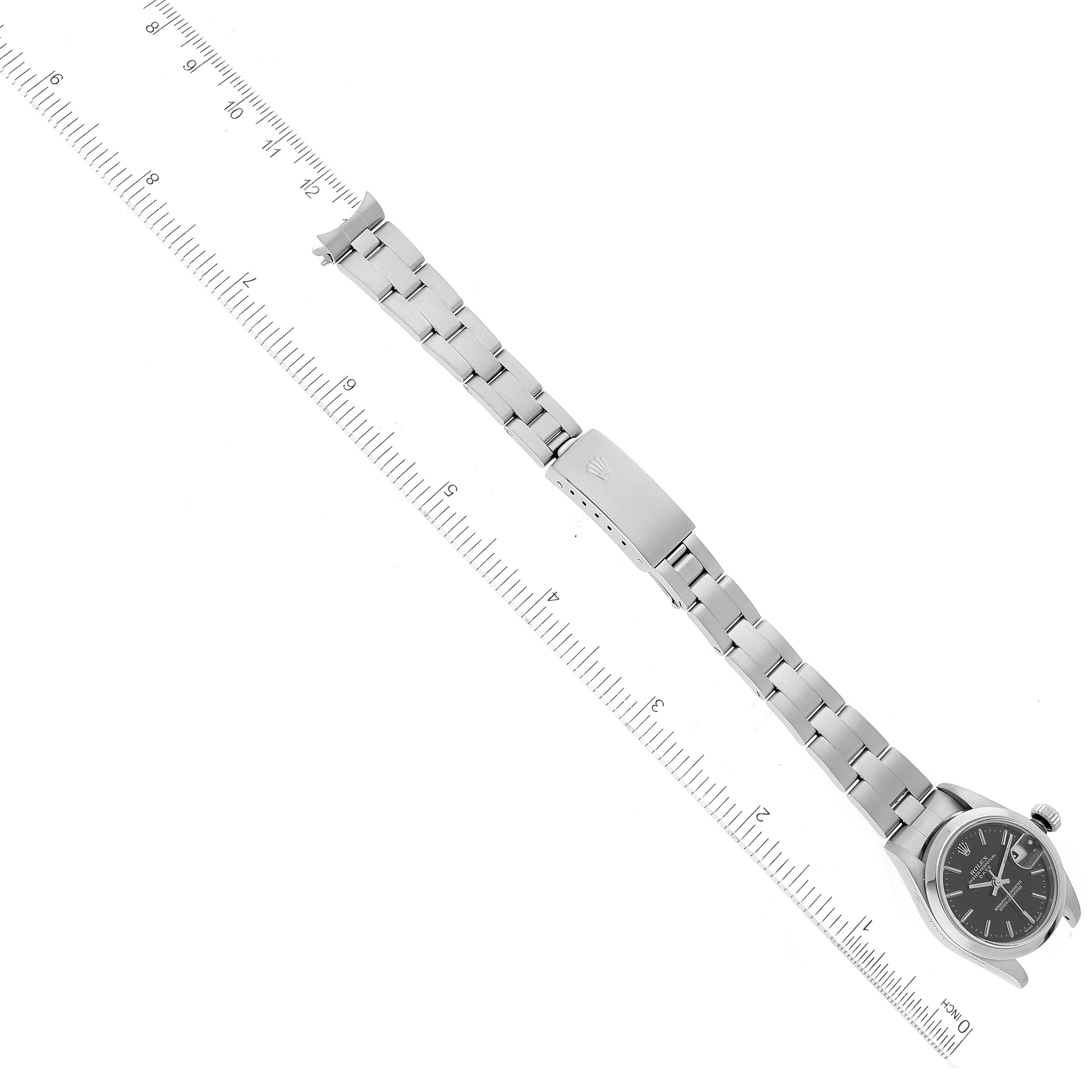 The image shows a Rolex Date 79160 Women's Stainless Steel Black Dial 79160 Women's Stainless Steel Black Dial model watch laid flat, showcasing its face, bracelet, and clasp, with a ruler for scale.