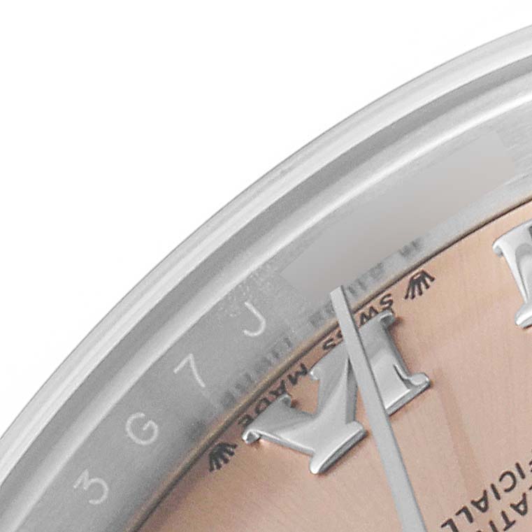 This close-up of a Rolex Datejust 279174 Women's Stainless Steel Pink Dial 279174 Women's Stainless Steel Pink Dial watch shows part of the dial, hands, and a segment of the bezel with serial numbers.