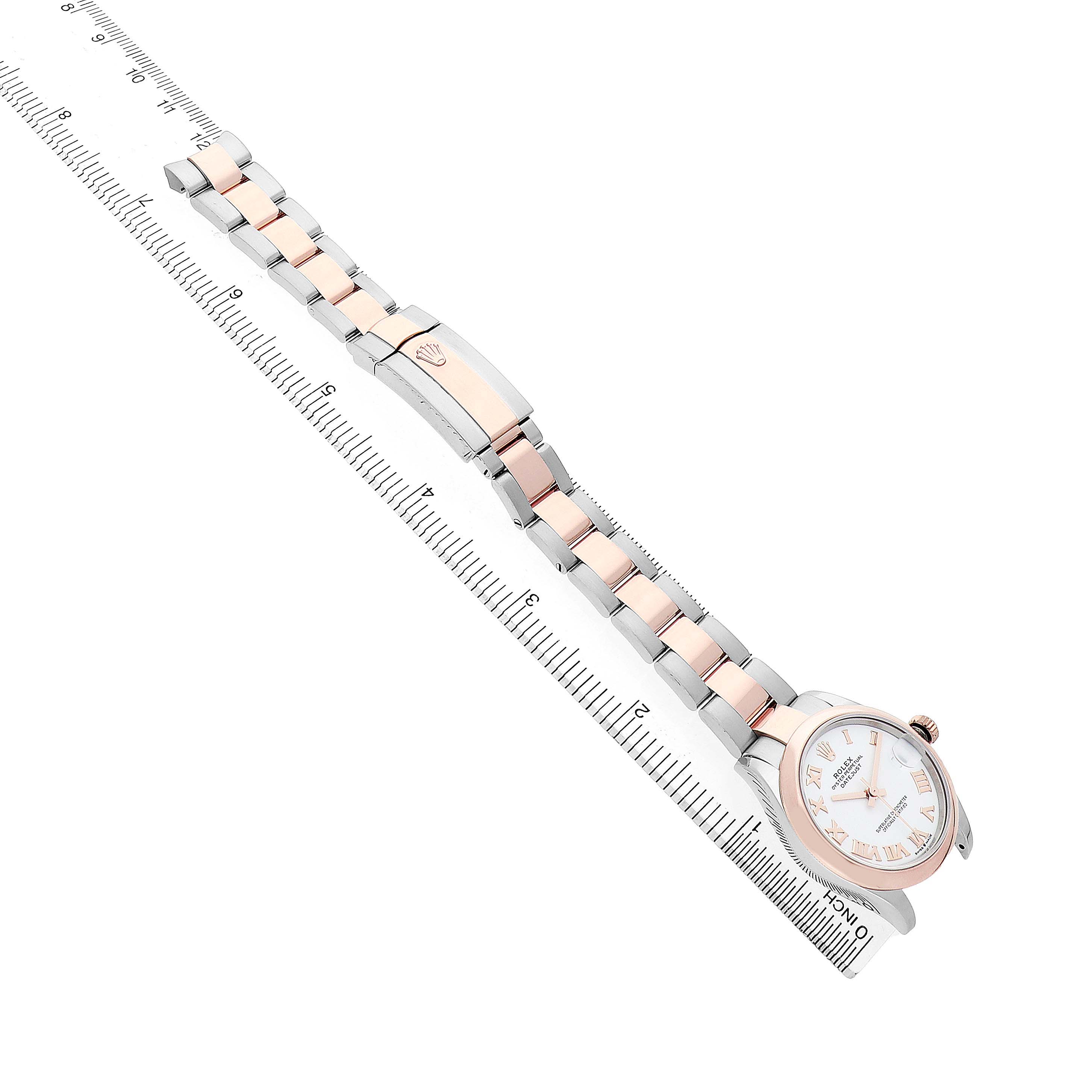 The Rolex Datejust 278241 Women's Stainless Steel White Dial watch is shown at an angle displaying its bracelet, clasp, and partially the face, laid alongside a ruler.