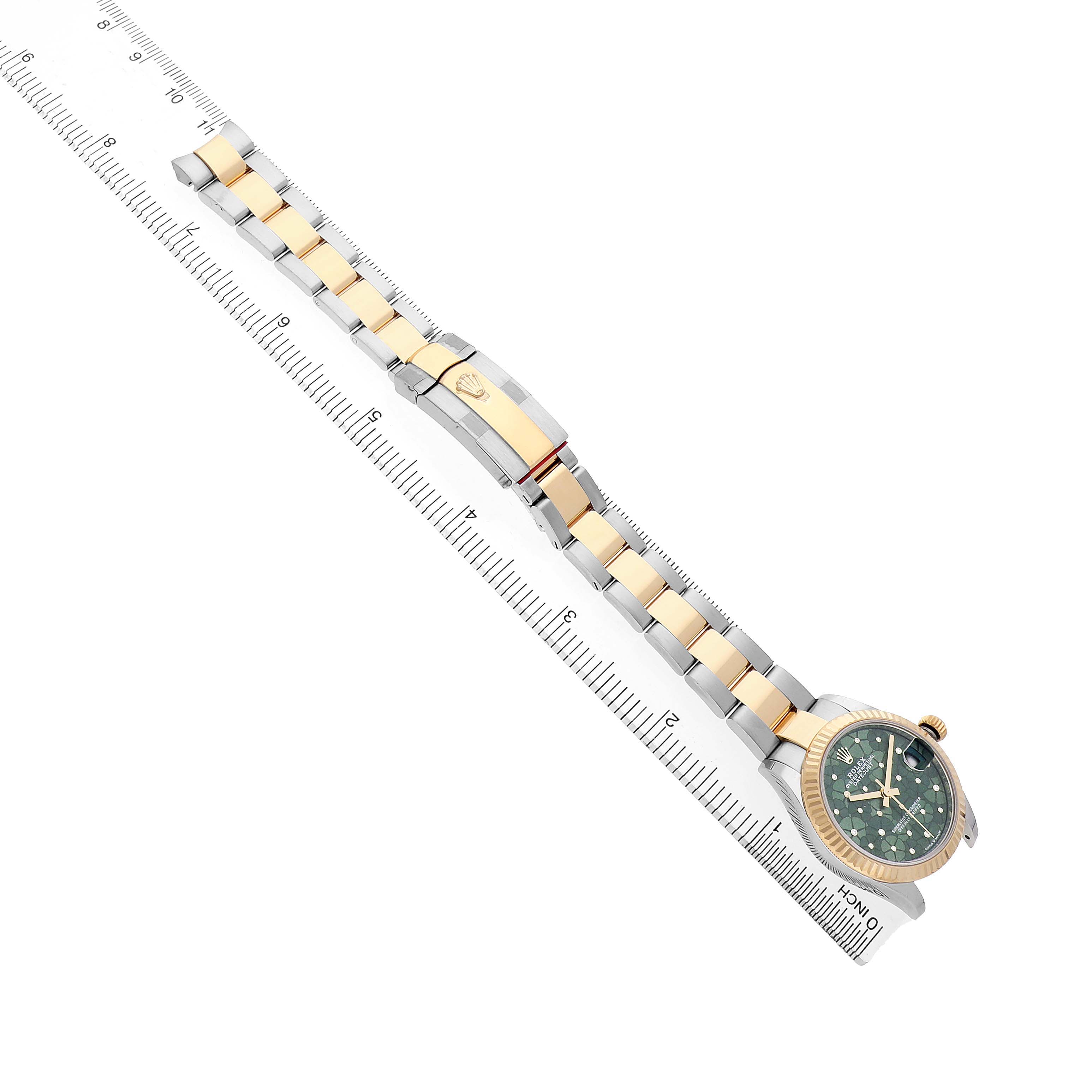 The Rolex Mid-Size 278273 Women's Steel and Gold (two tone) Green Dial watch is shown from a top angle, displaying the full bracelet and watch face against a measuring ruler.