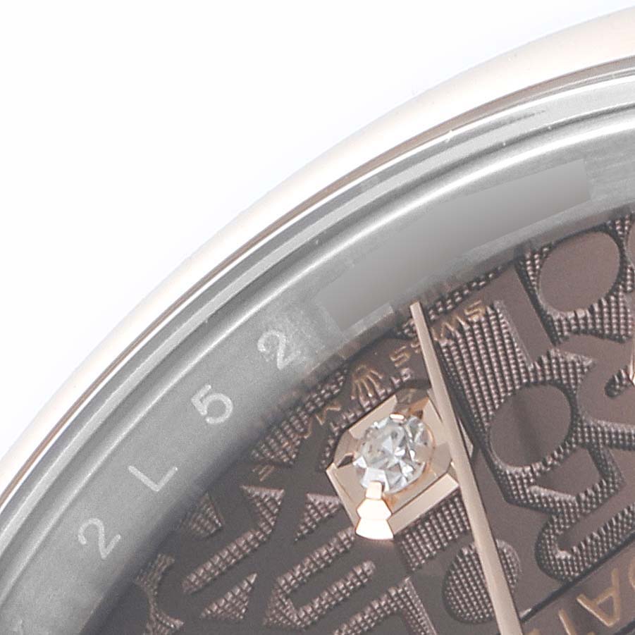 The close-up angle of this Rolex Datejust 126201 Men's Steel and Gold (two tone) Brown Dial 126201 Men's Steel and Gold (two tone) Brown Dial shows the edge of the dial, part of a diamond hour marker, and engraved numbers.