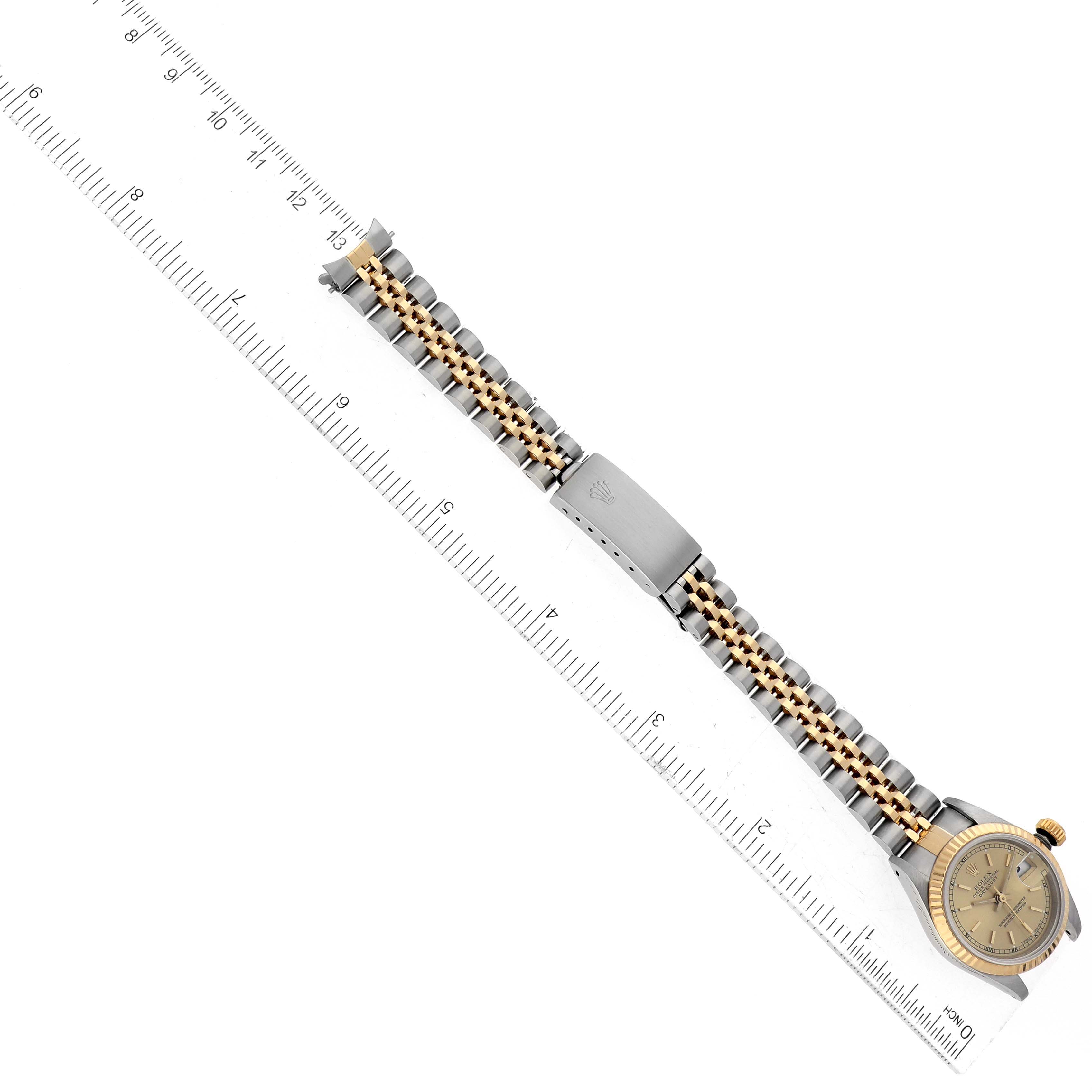 The image shows a top view of a Rolex Datejust 69173 Women's Steel and Gold (two tone) Champagne Dial 69173 Women's Steel and Gold (two tone) Champagne Dial watch alongside a ruler, highlighting its bracelet and clasp.