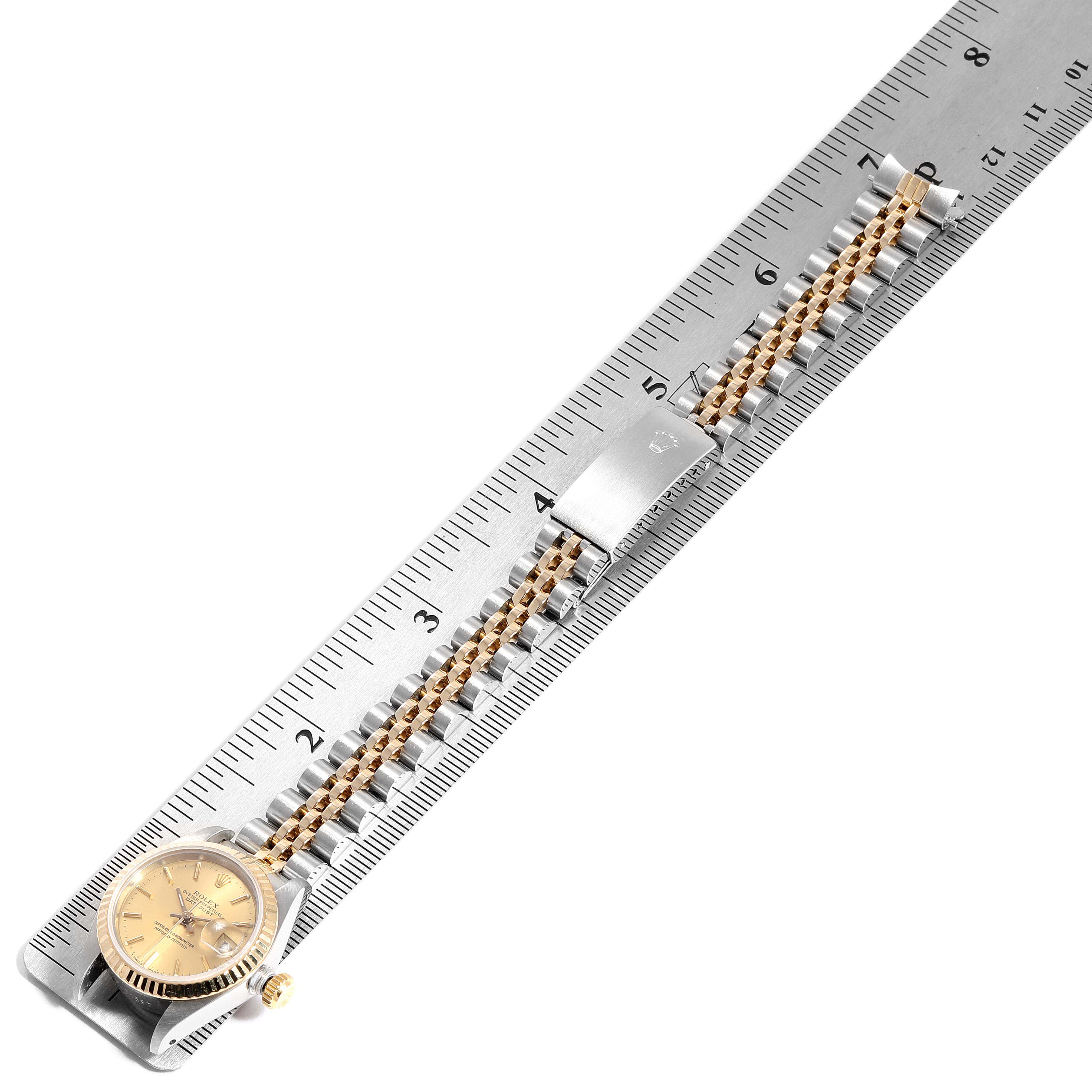 The image shows a Rolex Datejust 69173 Women
s Steel and Gold (two tone) Champagne Dial 69173 Women
s Steel and Gold (two tone) Champagne Dial watch with a stainless steel and gold bracelet laid flat alongside a ruler.