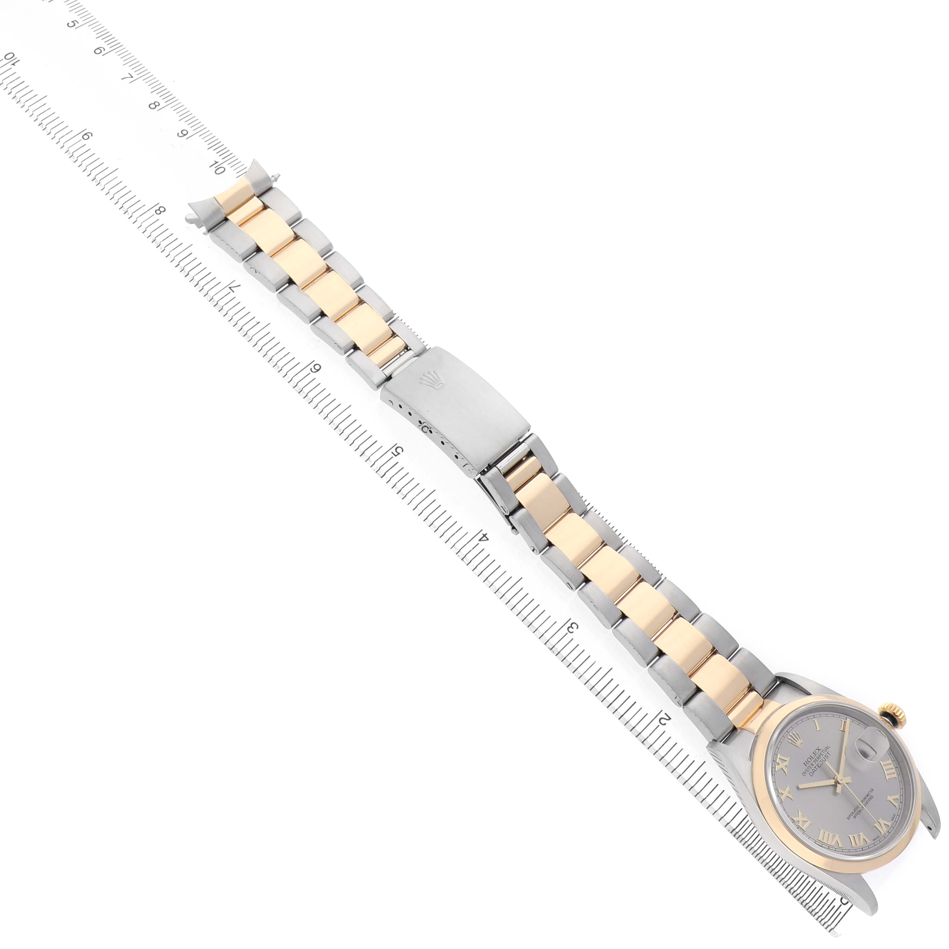 The Rolex Datejust 16203 Men's Steel and Gold (two tone) Silver Dial watch is shown at an angle, displaying its bracelet, dial, and clasp alongside a ruler for scale.