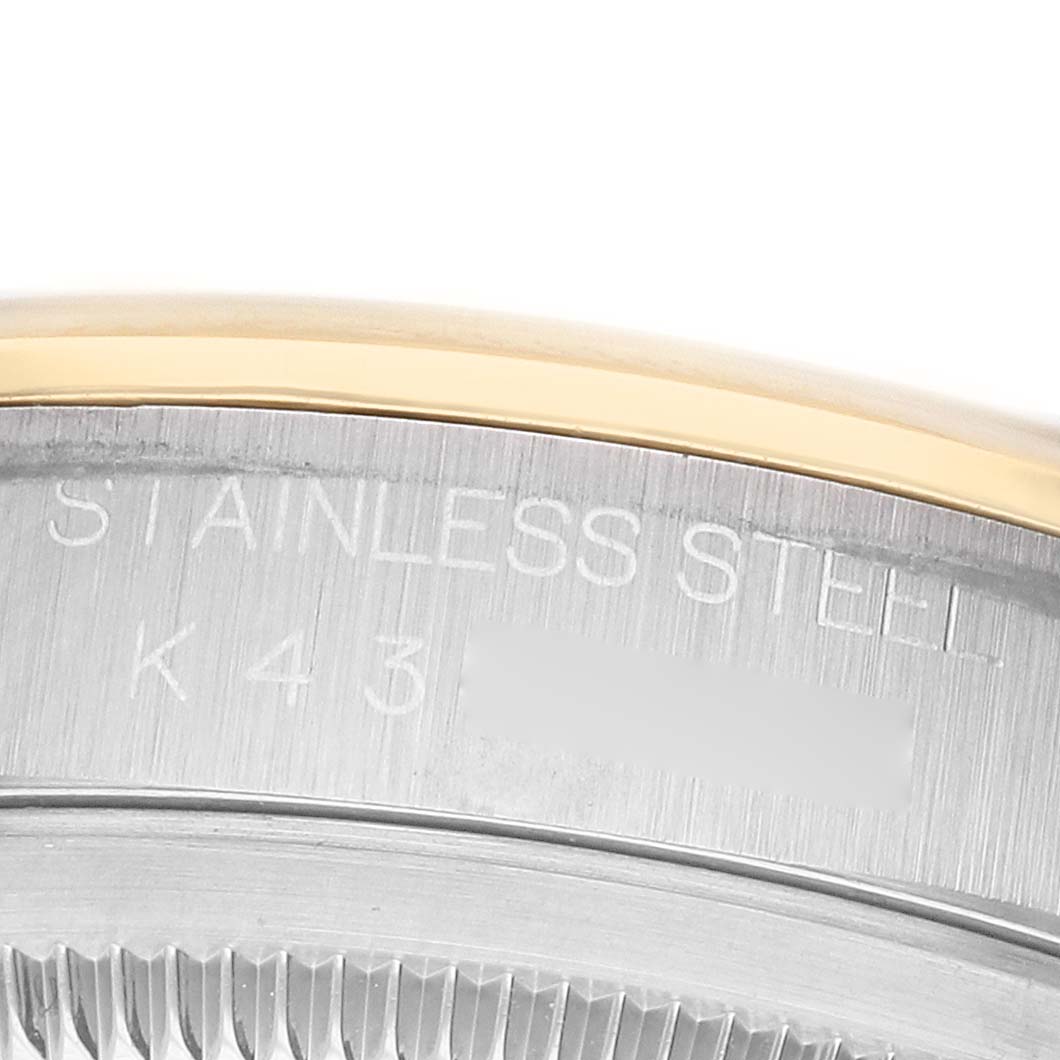 The image shows a close-up of the edge of the Rolex Datejust 16203 Men's Steel and Gold (two tone) Silver Dial watch, highlighting its stainless steel engraving and gold trim.