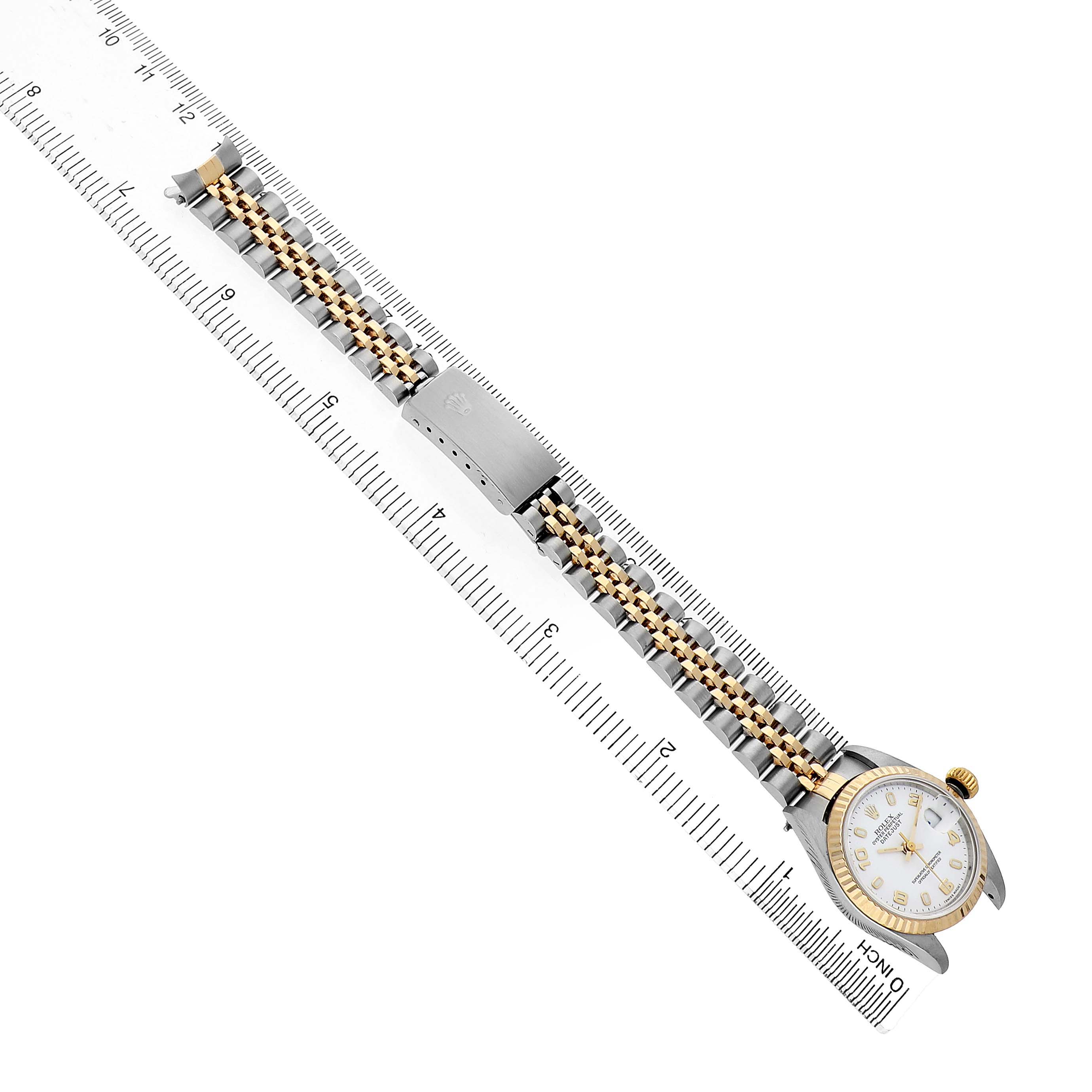 The Rolex Datejust 79173 Women's Stainless Steel White Dial watch is shown at a top-down angle, featuring the watch face, Jubilee bracelet, and clasp alongside a ruler.