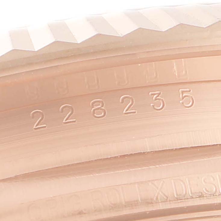The image shows a close-up angle of the bezel and engraved serial number of a Rolex President 228235 Men's Rose Gold Brown Dial 228235 Men's Rose Gold Brown Dial model watch.